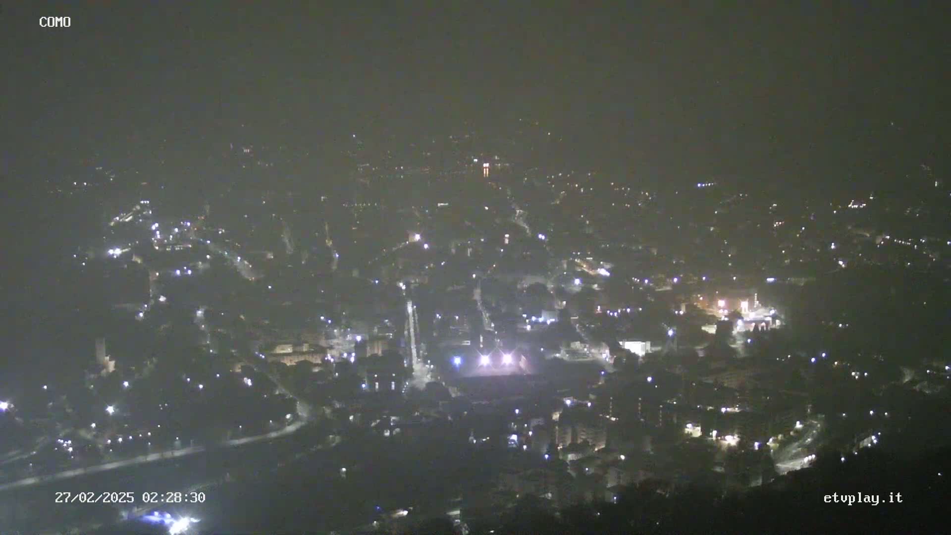 A hazy night view of a city illuminated by scattered lights.