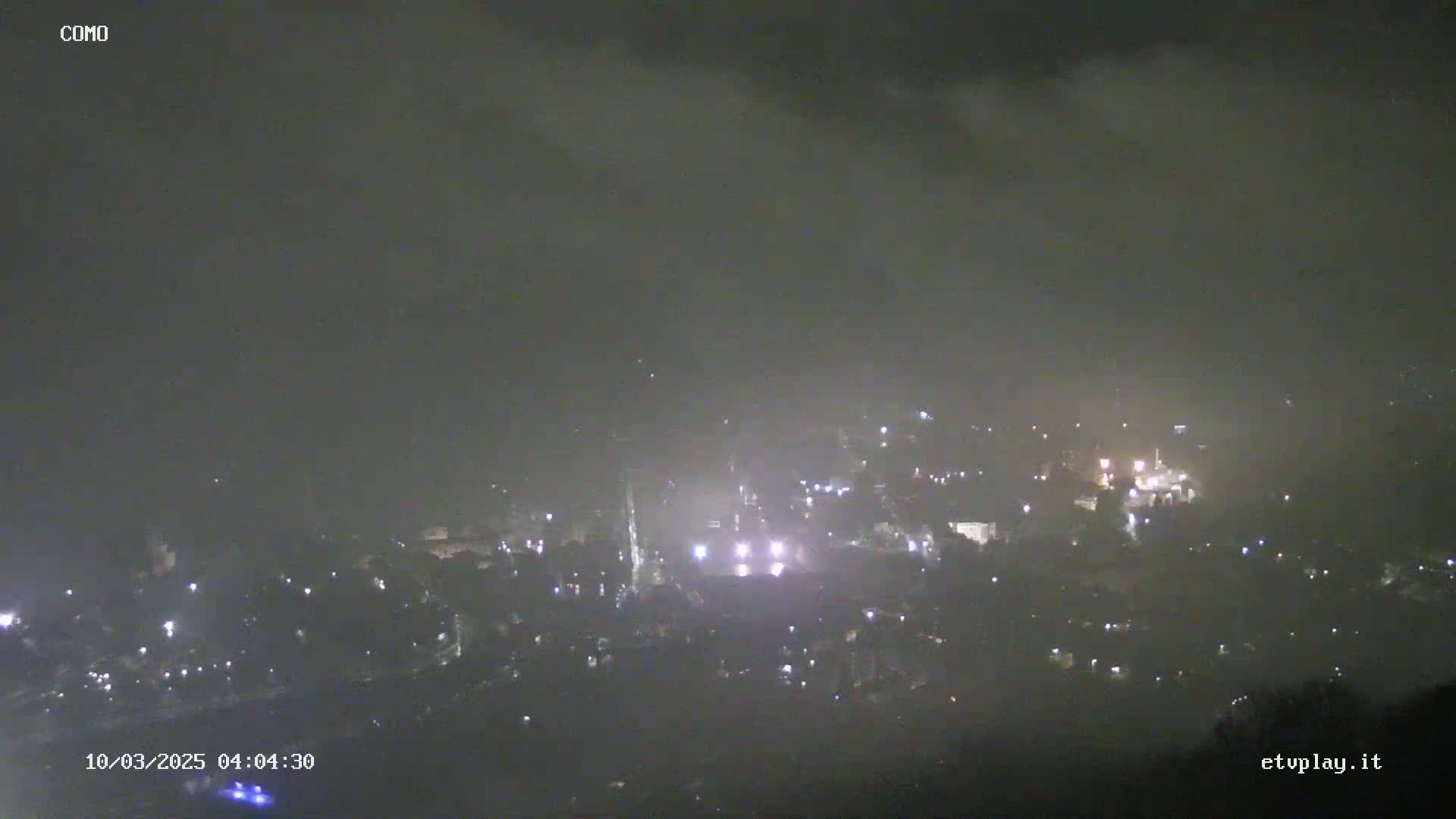 A nighttime, hazy view of a town with scattered lights.