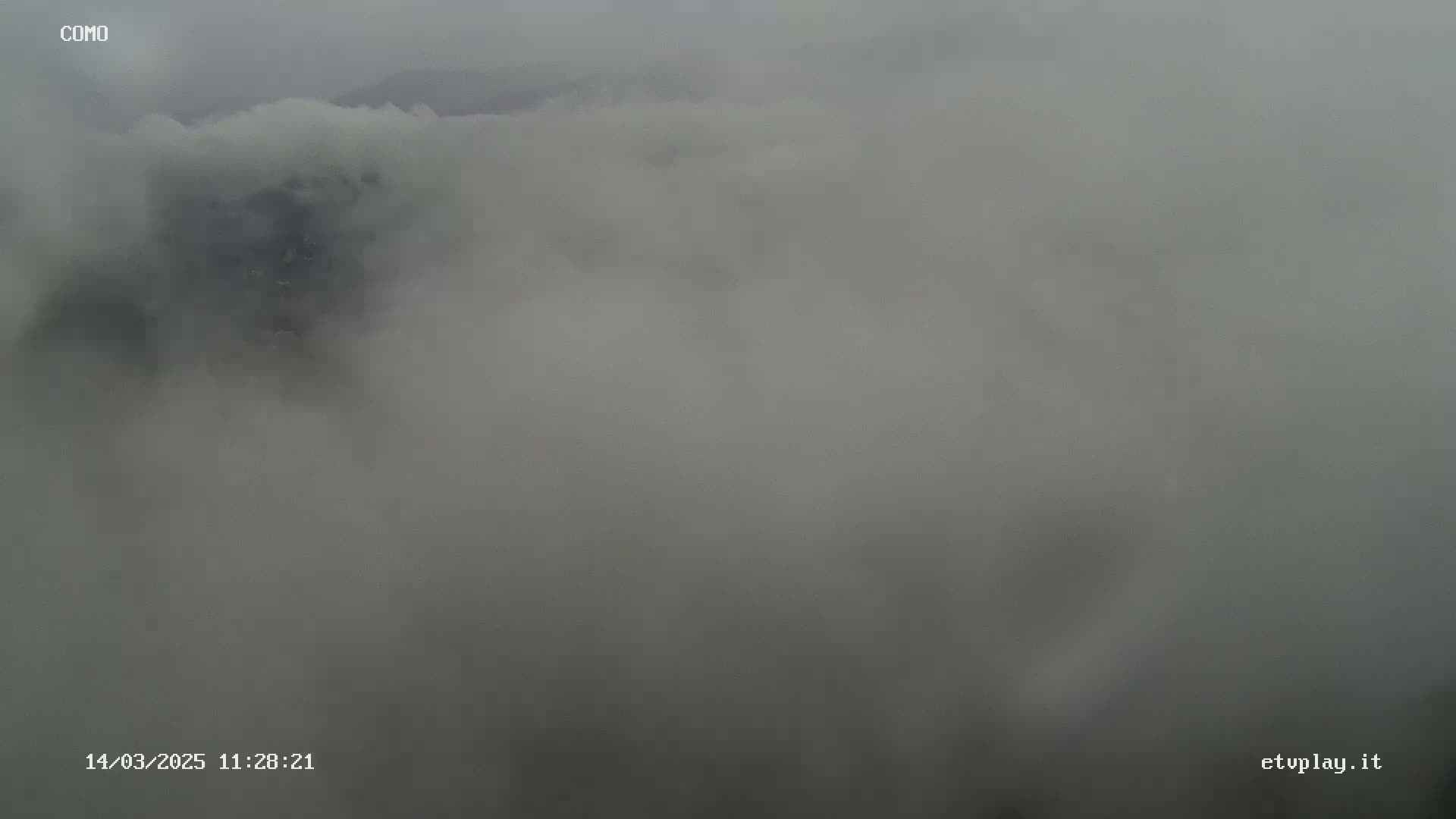 A landscape is obscured by a thick layer of fog or low-hanging clouds.