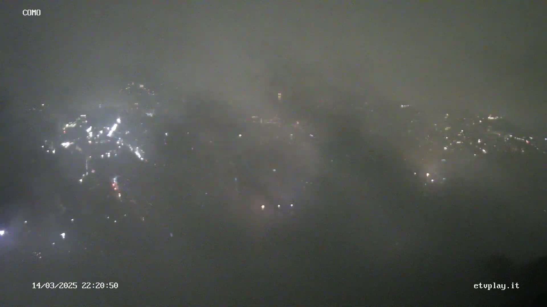 A nighttime, foggy view shows a distant city with scattered lights.