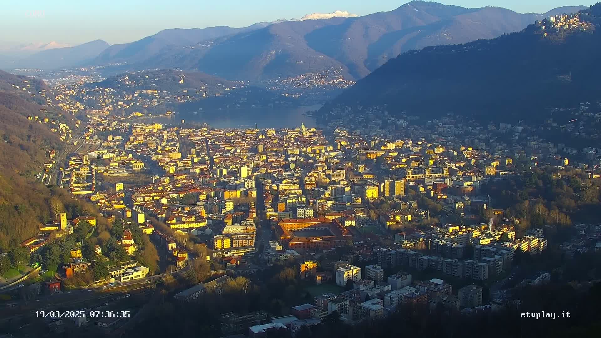 A sprawling city nestled in a valley between mountains, bathed in the golden light of sunrise or sunset.