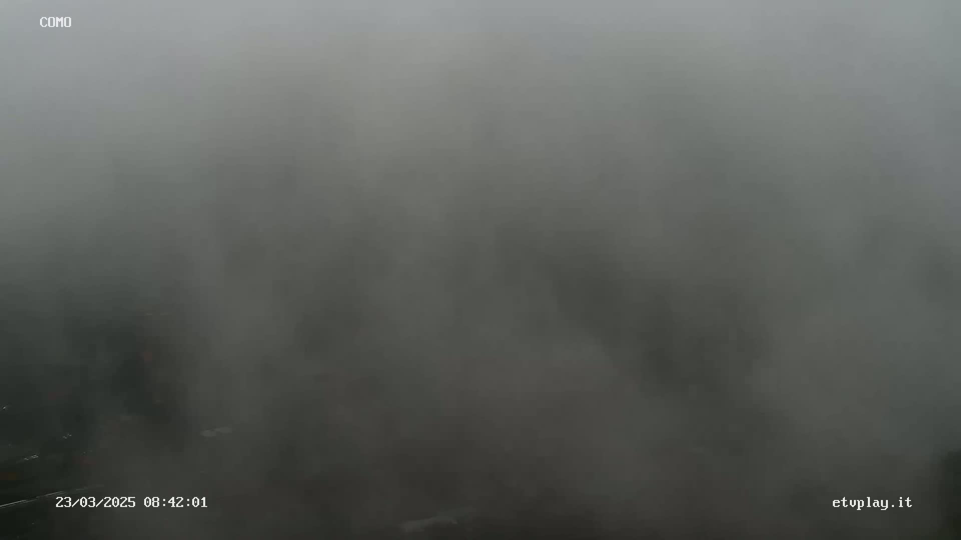 A very foggy or misty outdoor scene is visible, obscuring any details beyond a very short distance.