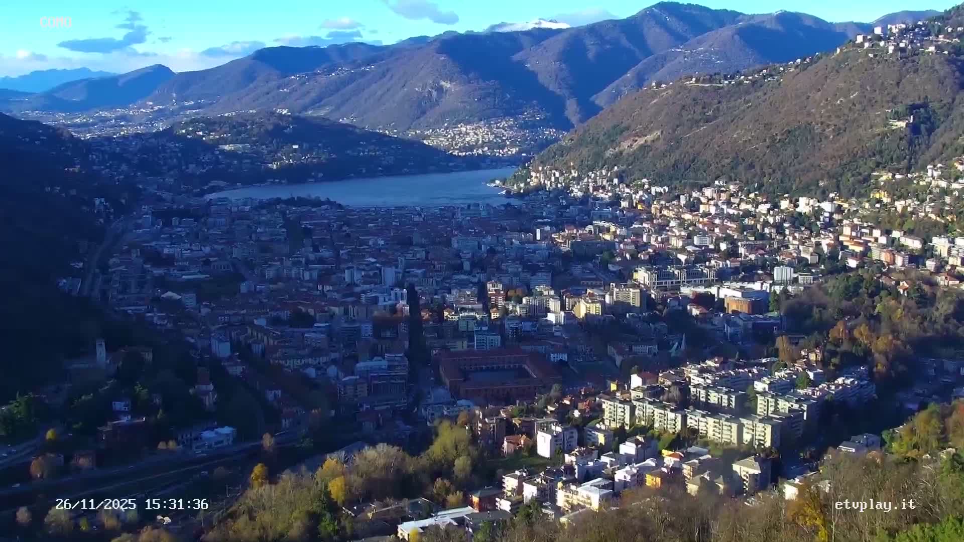 An aerial view of a city is heavily obscured by dense fog and rain droplets on the camera lens, creating a hazy and muted scene.
