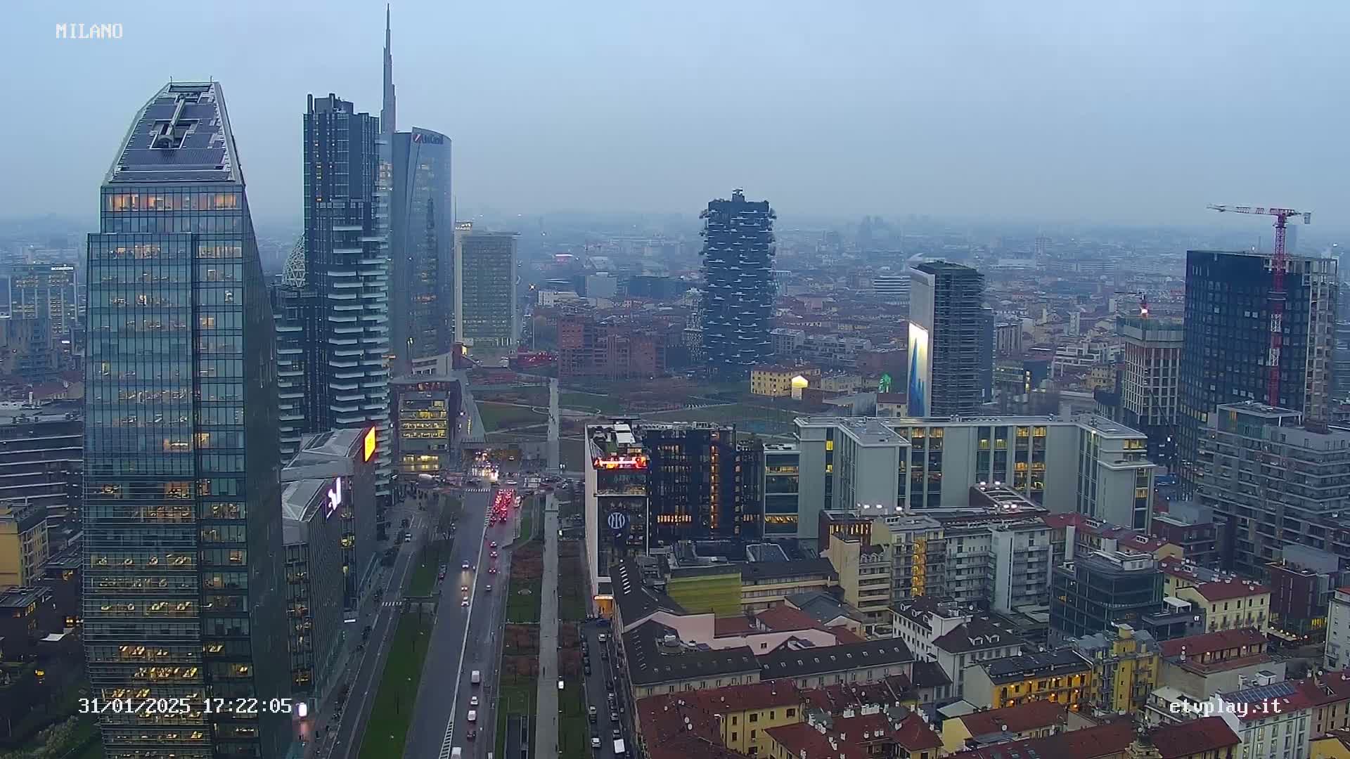 A hazy, overcast cityscape view of numerous modern skyscrapers and buildings, with a multi-lane road running through the foreground.