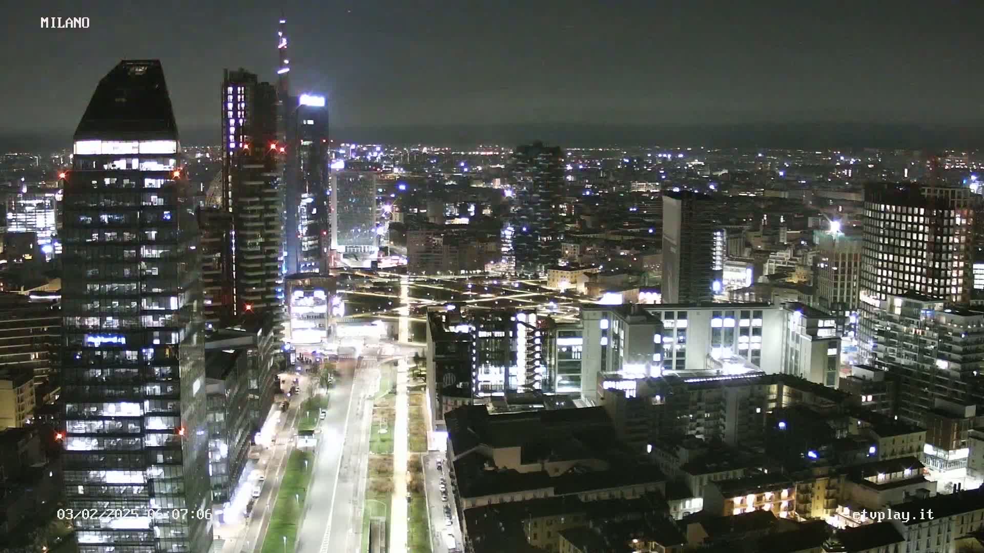 A nighttime aerial view of a densely populated city with many illuminated buildings and streets.