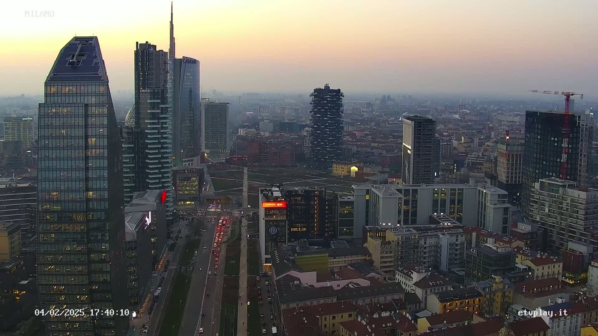 An aerial view of a city skyline at dusk, showing numerous skyscrapers and a hazy atmosphere.