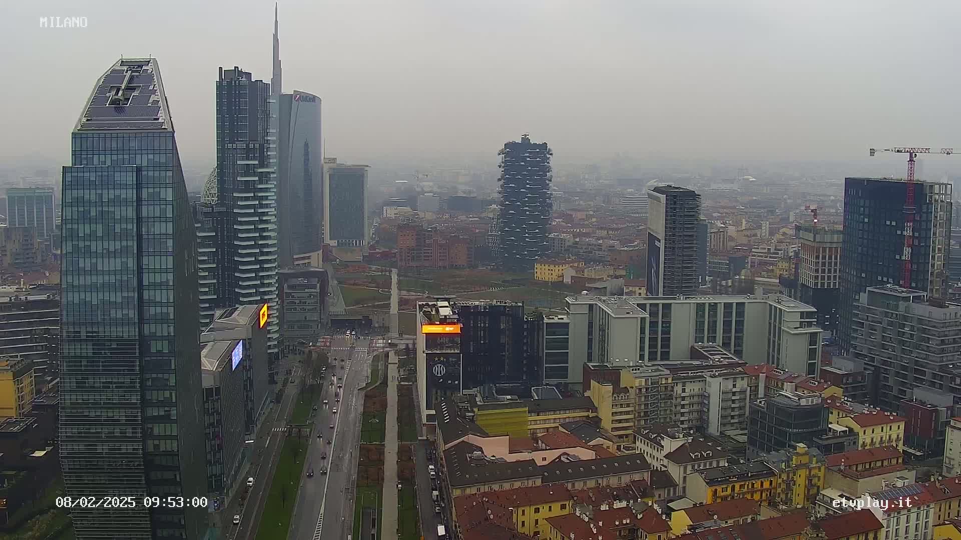 A hazy view of a city skyline shows numerous skyscrapers and high-rise buildings, with a highway visible in the foreground.