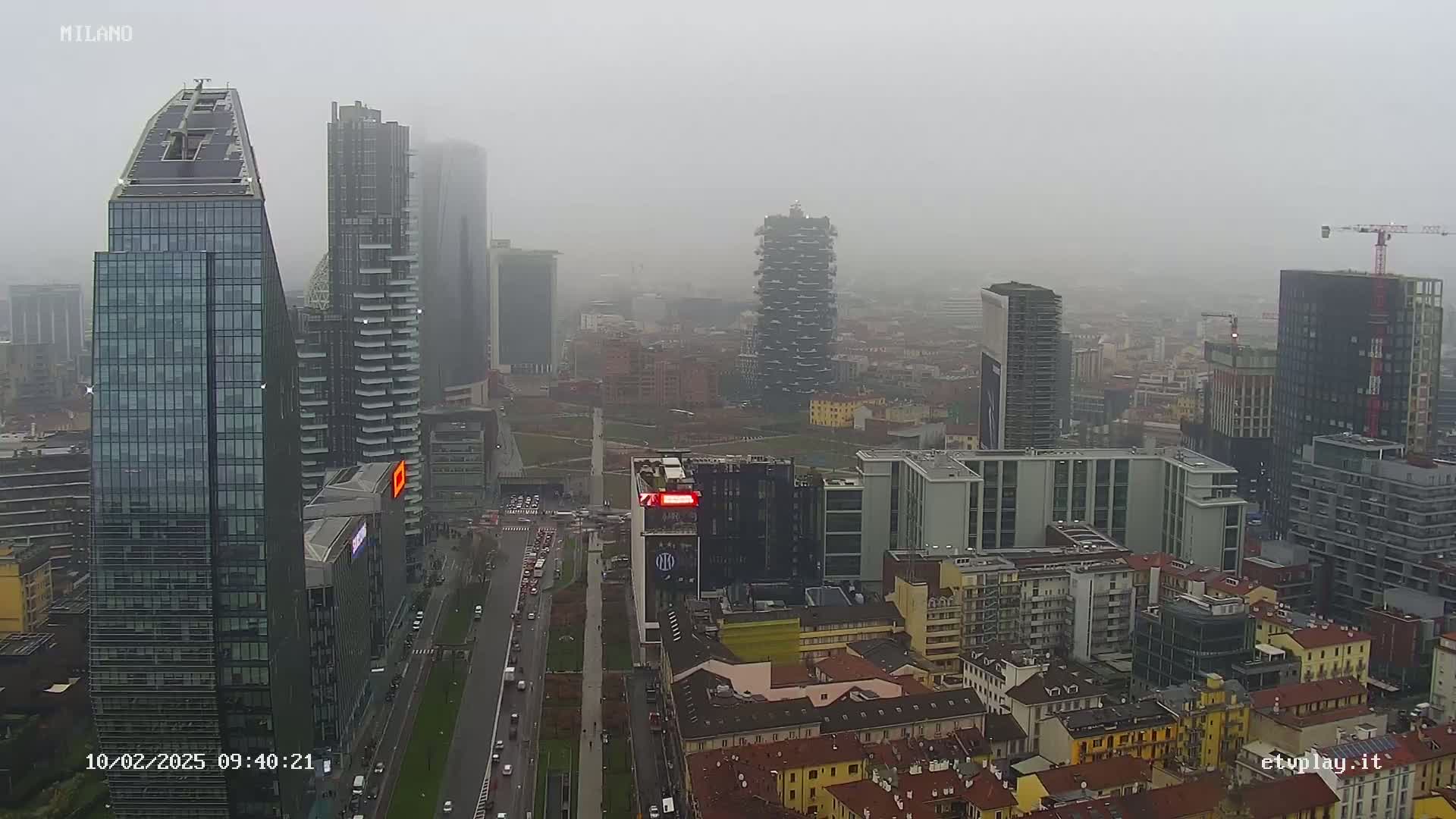 A foggy cityscape of numerous skyscrapers and buildings, with a road visible below.