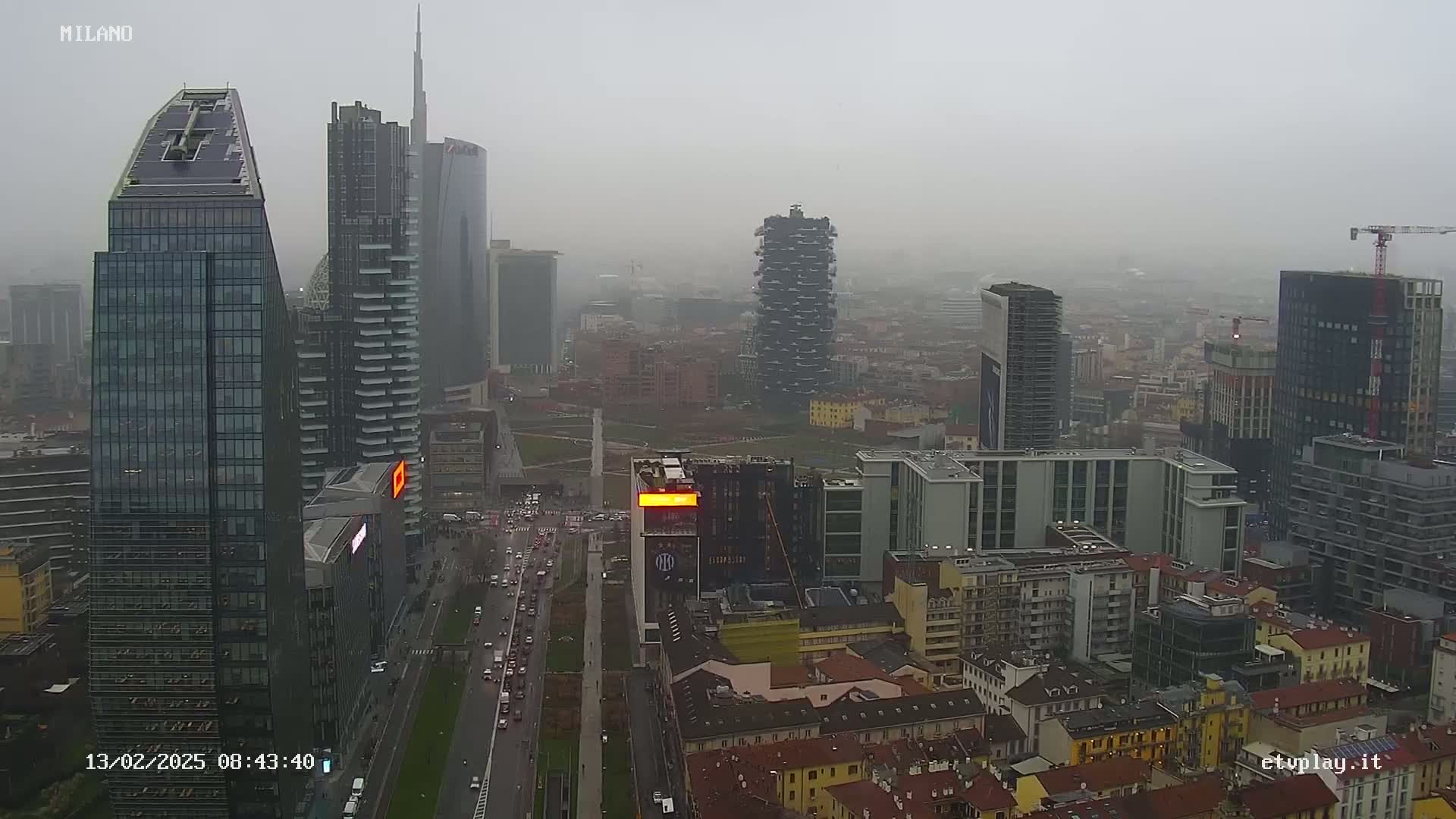 A city skyline with numerous skyscrapers and high-rise buildings under a hazy, overcast sky.