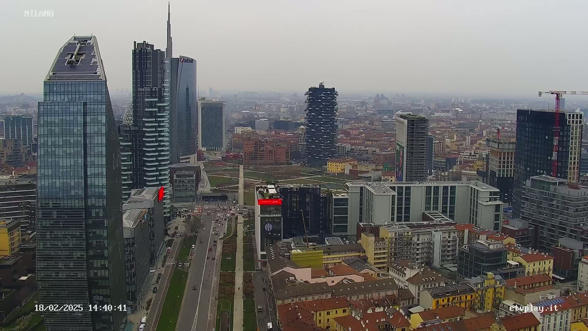 An aerial view of a dense cityscape of mostly modern skyscrapers on an overcast day.
