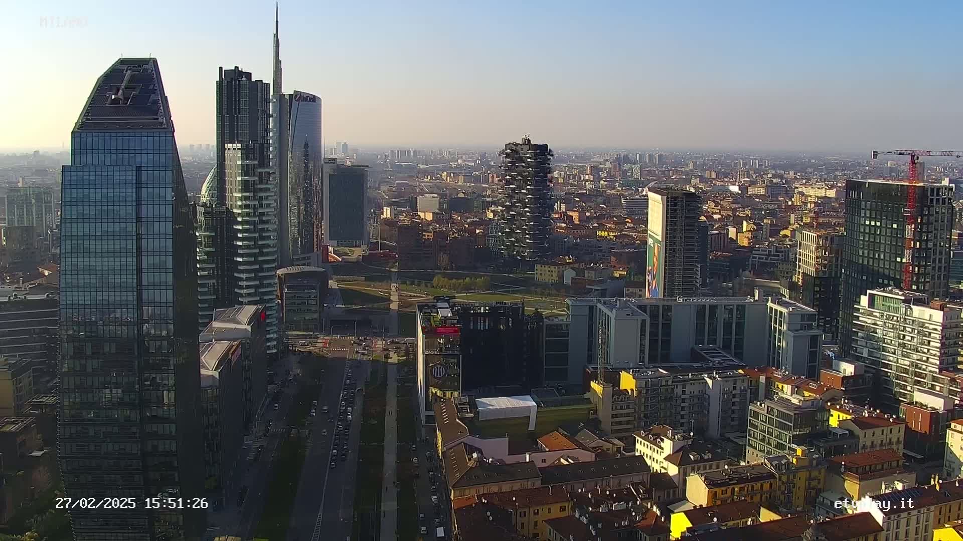 An aerial view of a city skyline with numerous skyscrapers on a partly sunny day.