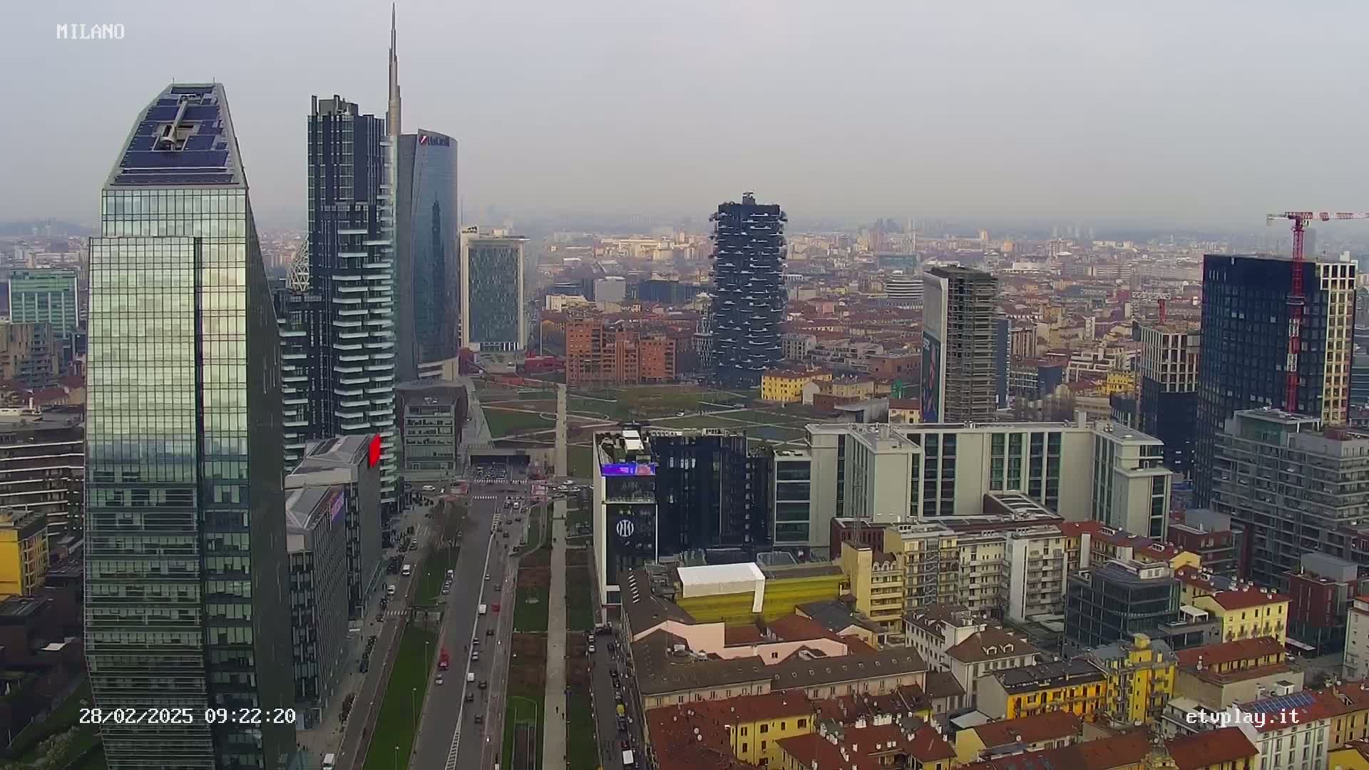 An aerial view of a city with many modern skyscrapers under an overcast sky.