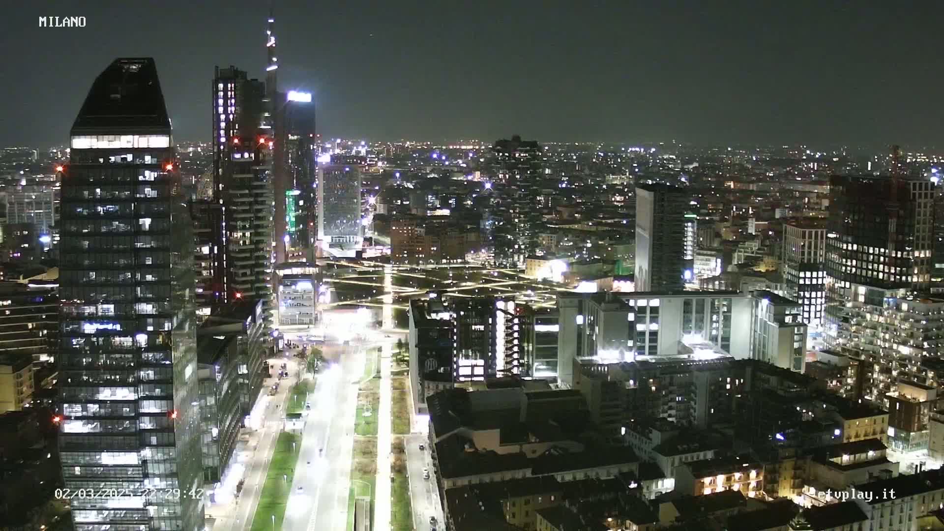 A nighttime aerial view of a city, showing numerous illuminated buildings and streets.