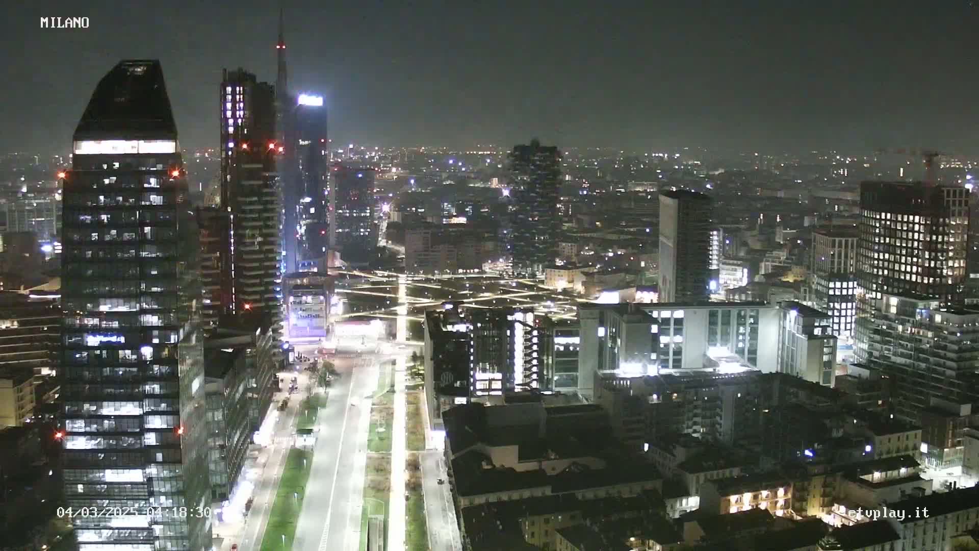 A nighttime aerial view of a city's skyline, showing numerous illuminated buildings and streets.