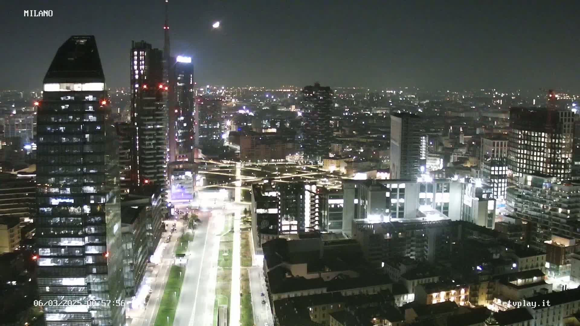 A nighttime, high-angle view of a city skyline with many illuminated buildings and streets.