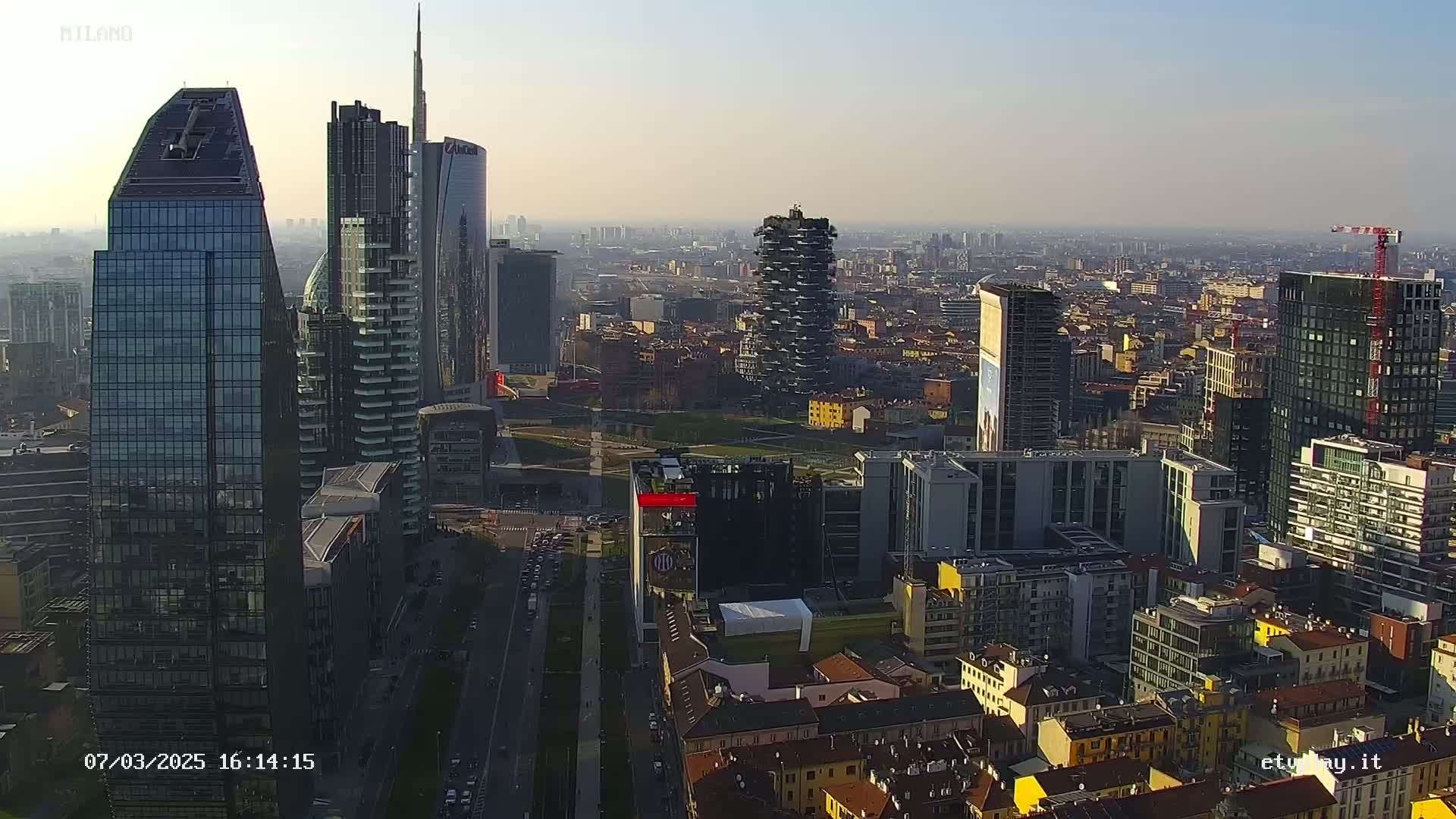 An aerial view of a city's skyline, featuring numerous skyscrapers and high-rise buildings on a hazy day.