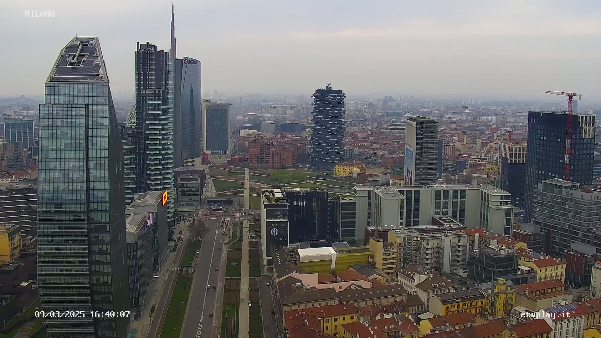 An aerial view of a city skyline on an overcast day, showing numerous skyscrapers and surrounding buildings.