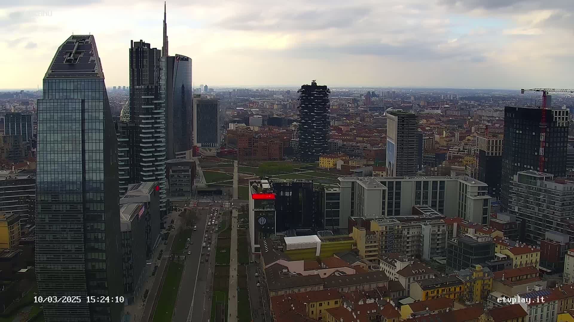 An aerial view of a city with numerous skyscrapers under a cloudy sky.