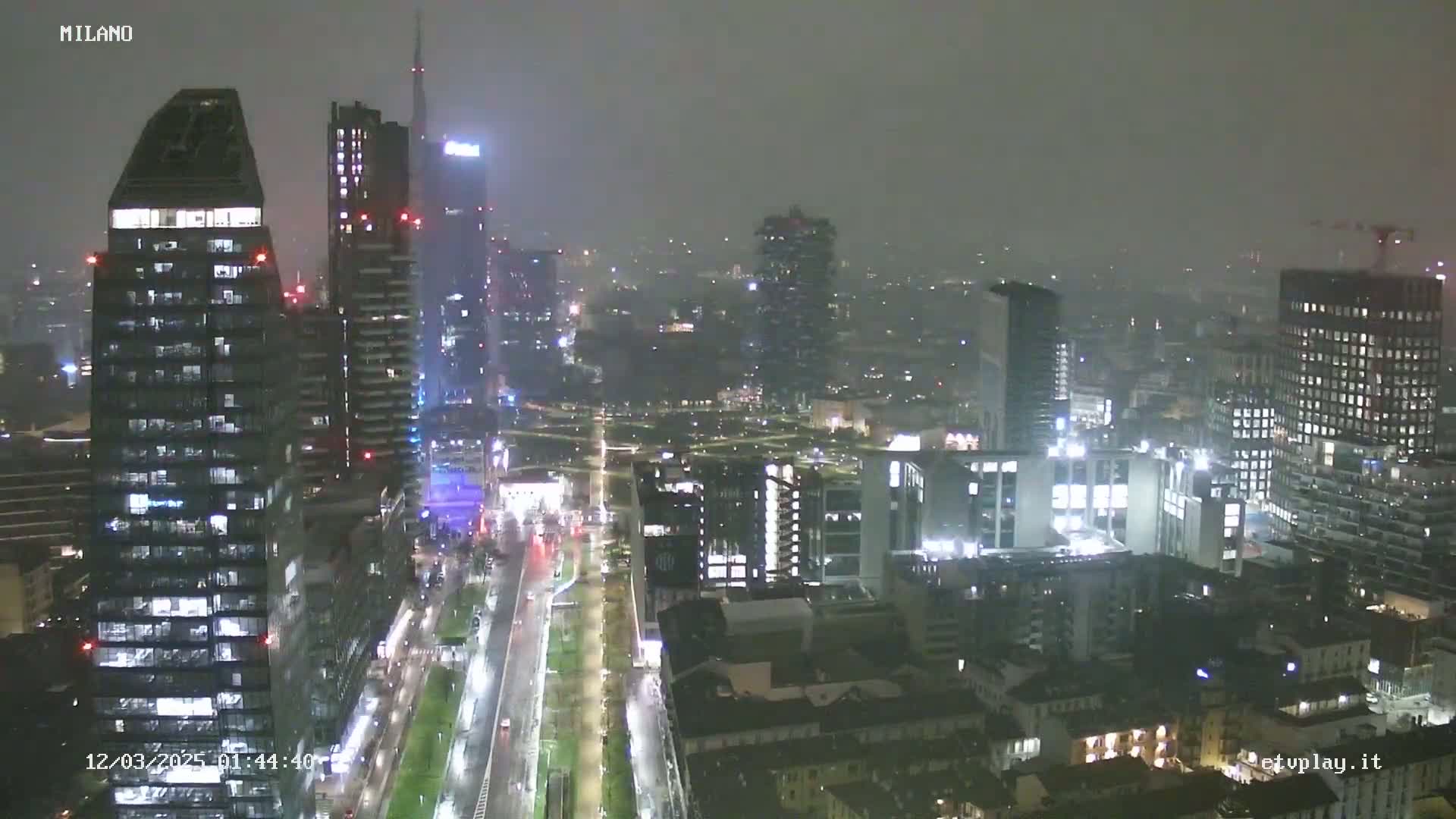 A nighttime, foggy view of a city skyline with many tall buildings illuminated.
