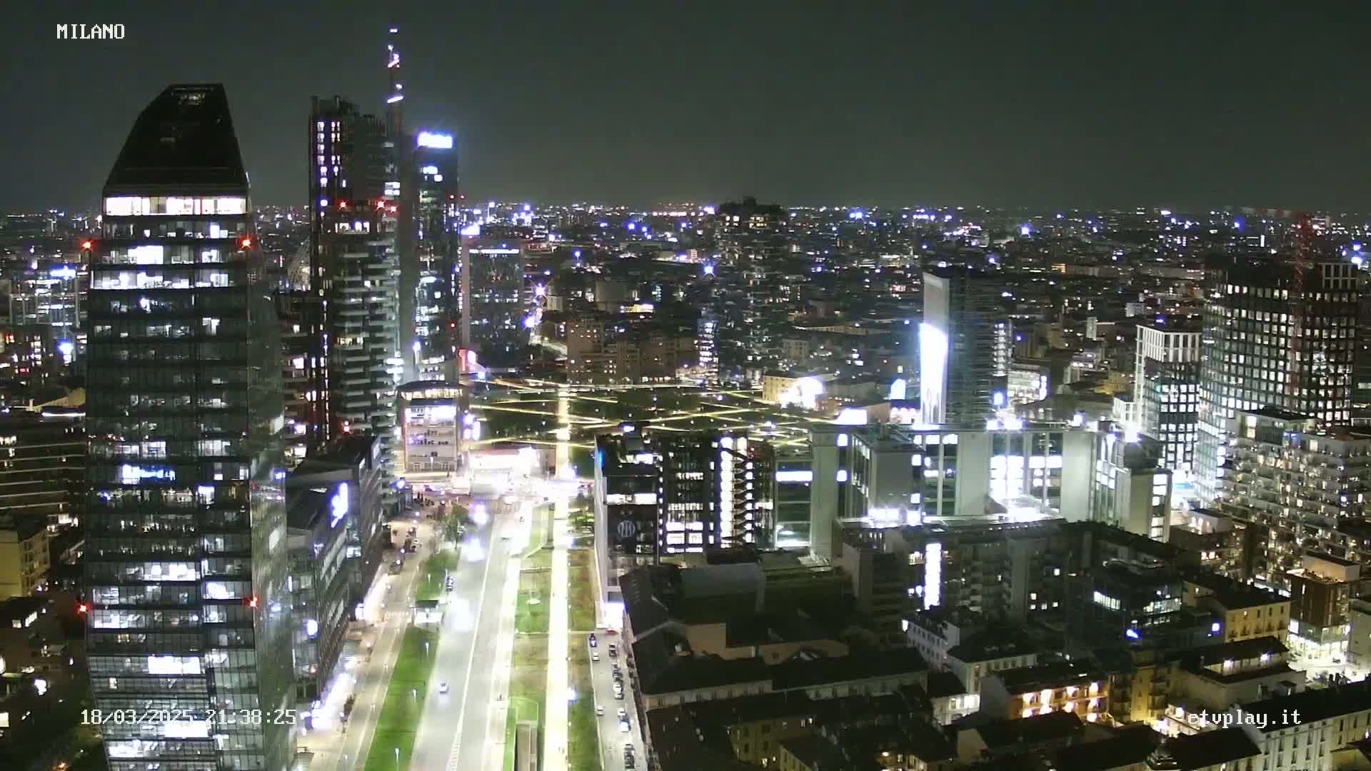 A nighttime aerial view of a city with numerous illuminated skyscrapers and buildings, showcasing a clear, dark sky.