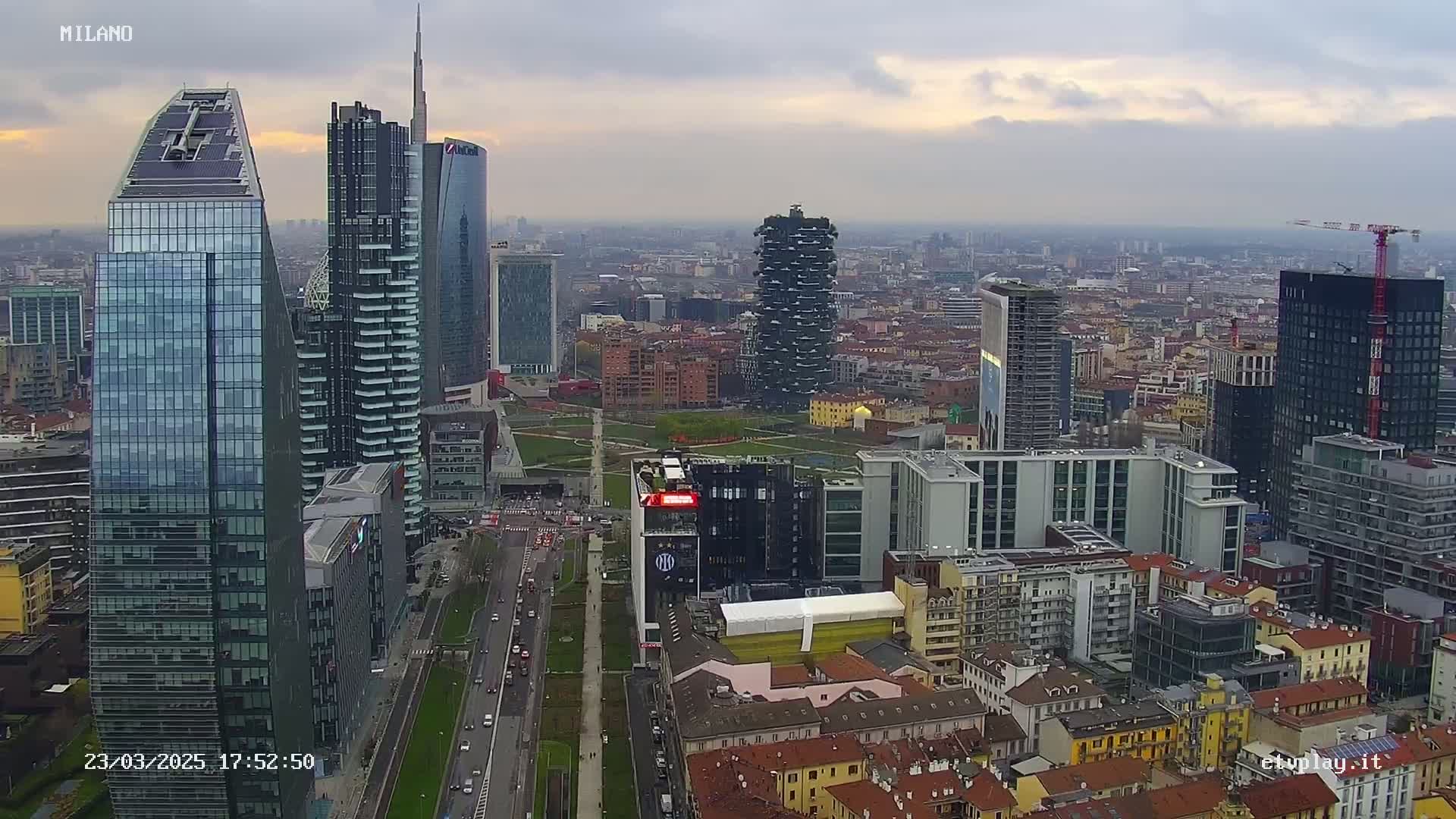 An aerial view of a city skyline with numerous skyscrapers under a cloudy sky.