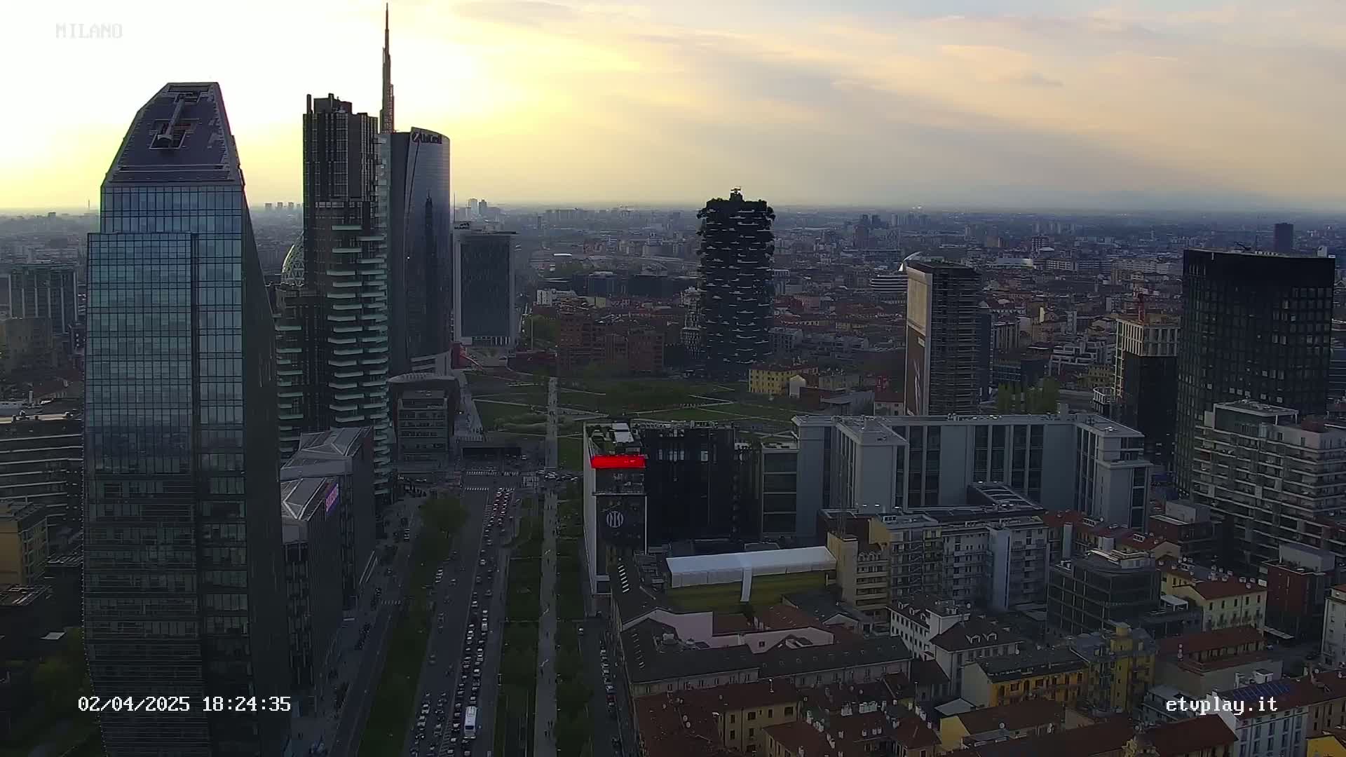 An aerial view of a city skyline at sunset, showing many skyscrapers and surrounding buildings.