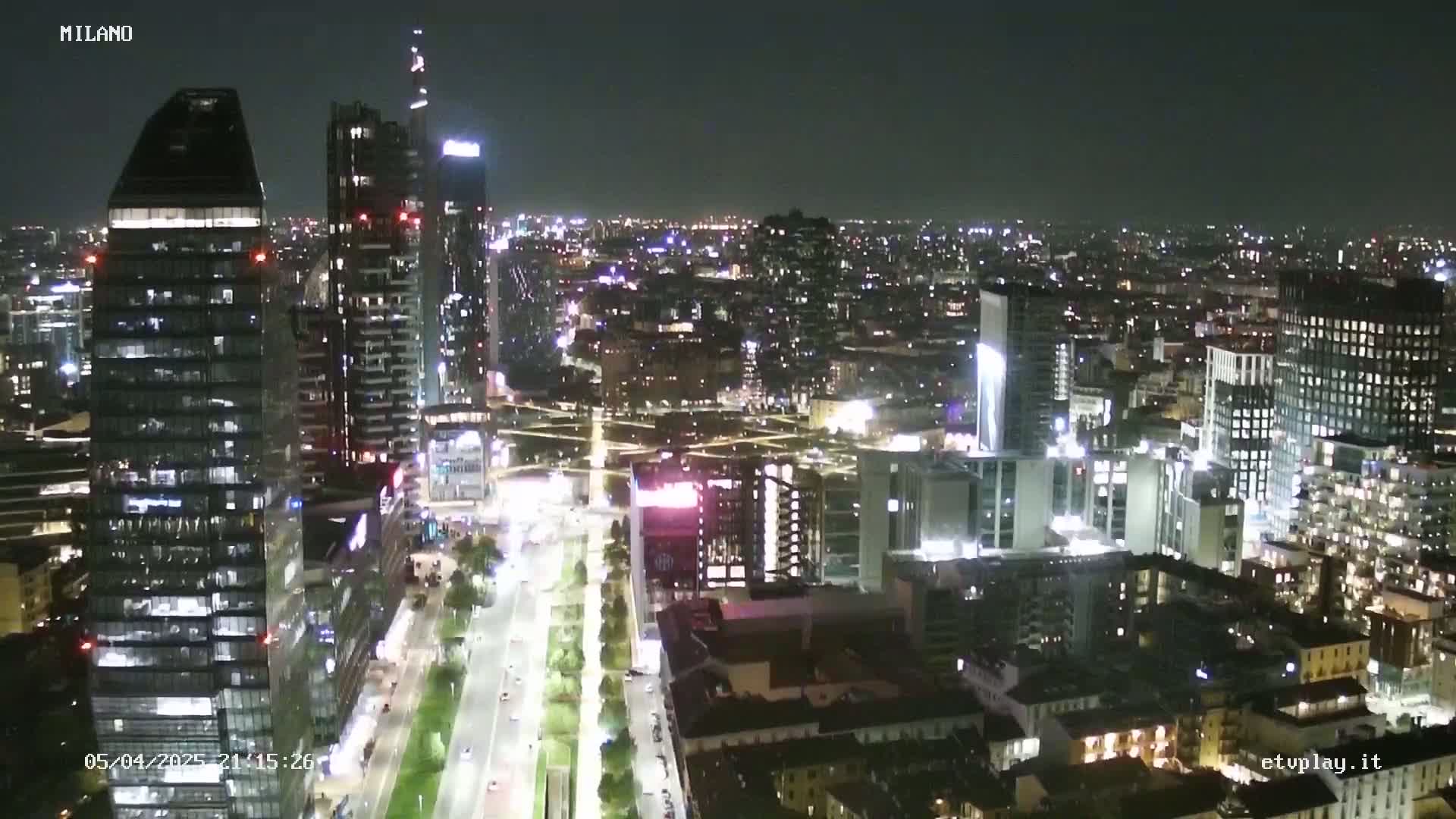 A nighttime aerial view of a city with many tall buildings and brightly lit streets.