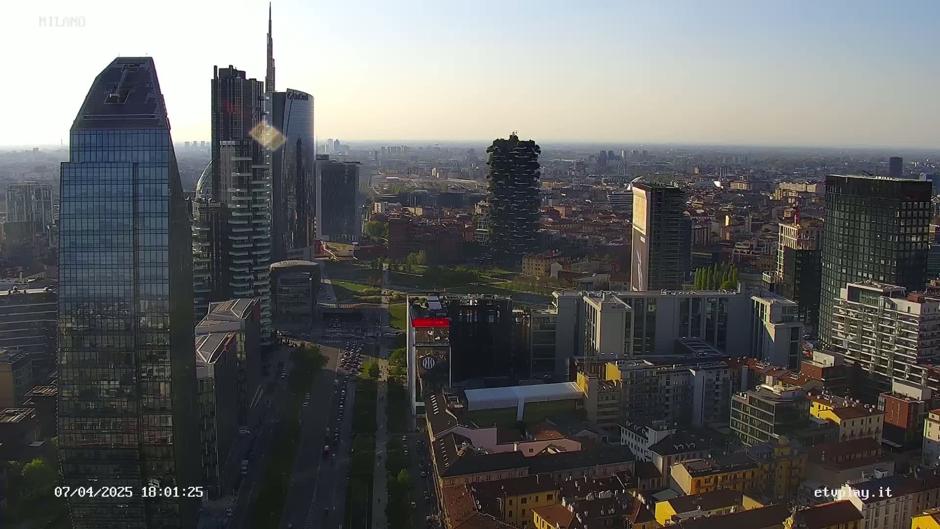 A high-angle, long shot of a cityscape with numerous skyscrapers under a hazy, bright sky.