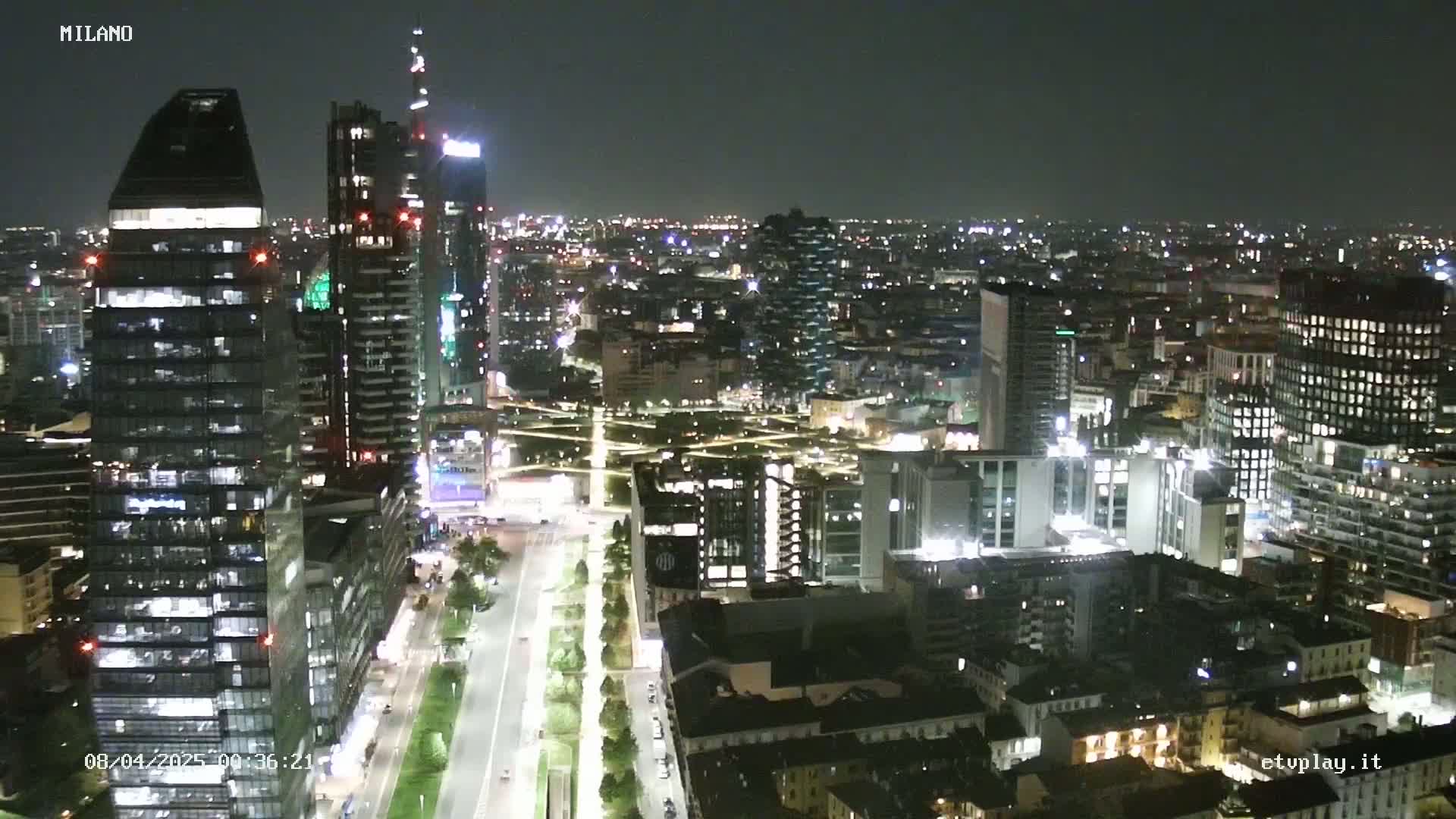 A nighttime aerial view of a city, showing numerous illuminated buildings and streets.