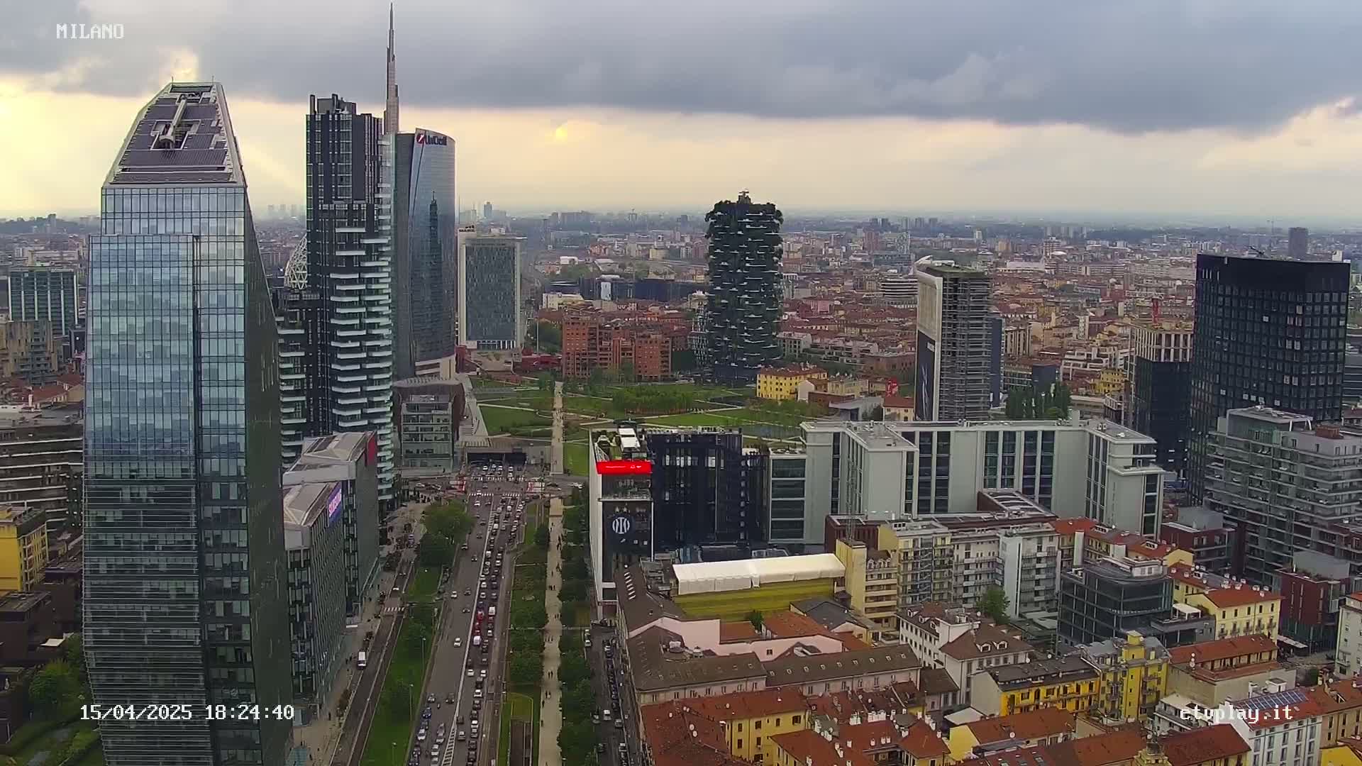 An aerial view of a city's skyline, featuring numerous skyscrapers and high-rise buildings under a cloudy sky.