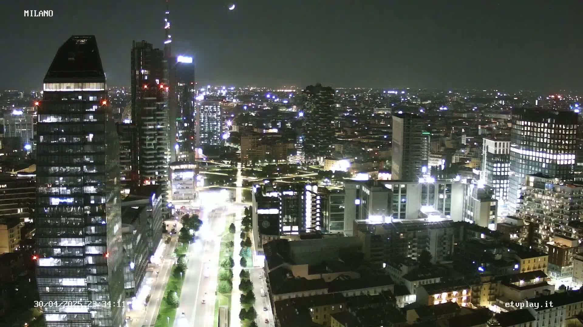 A nighttime aerial view of a city with many illuminated skyscrapers and streets.
