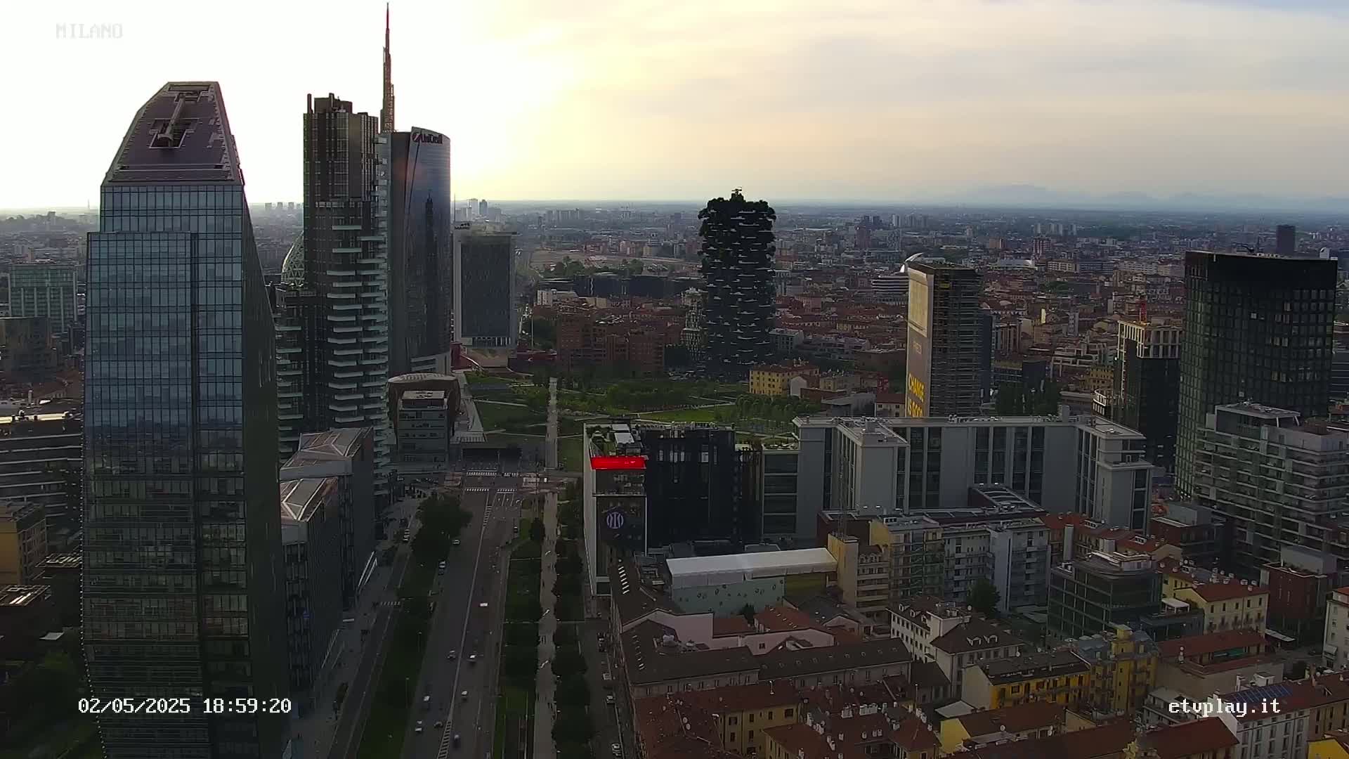 An aerial view of a city skyline with numerous skyscrapers under a hazy, overcast sky.