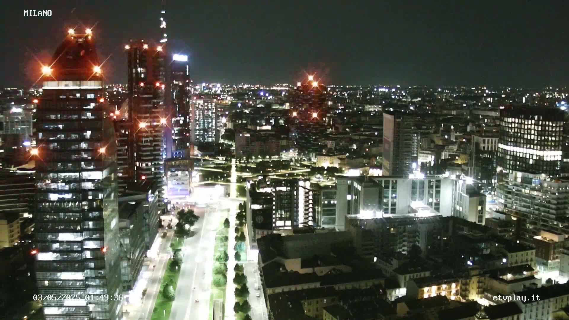 A nighttime aerial view of a city with many illuminated buildings and roads, under a clear sky.