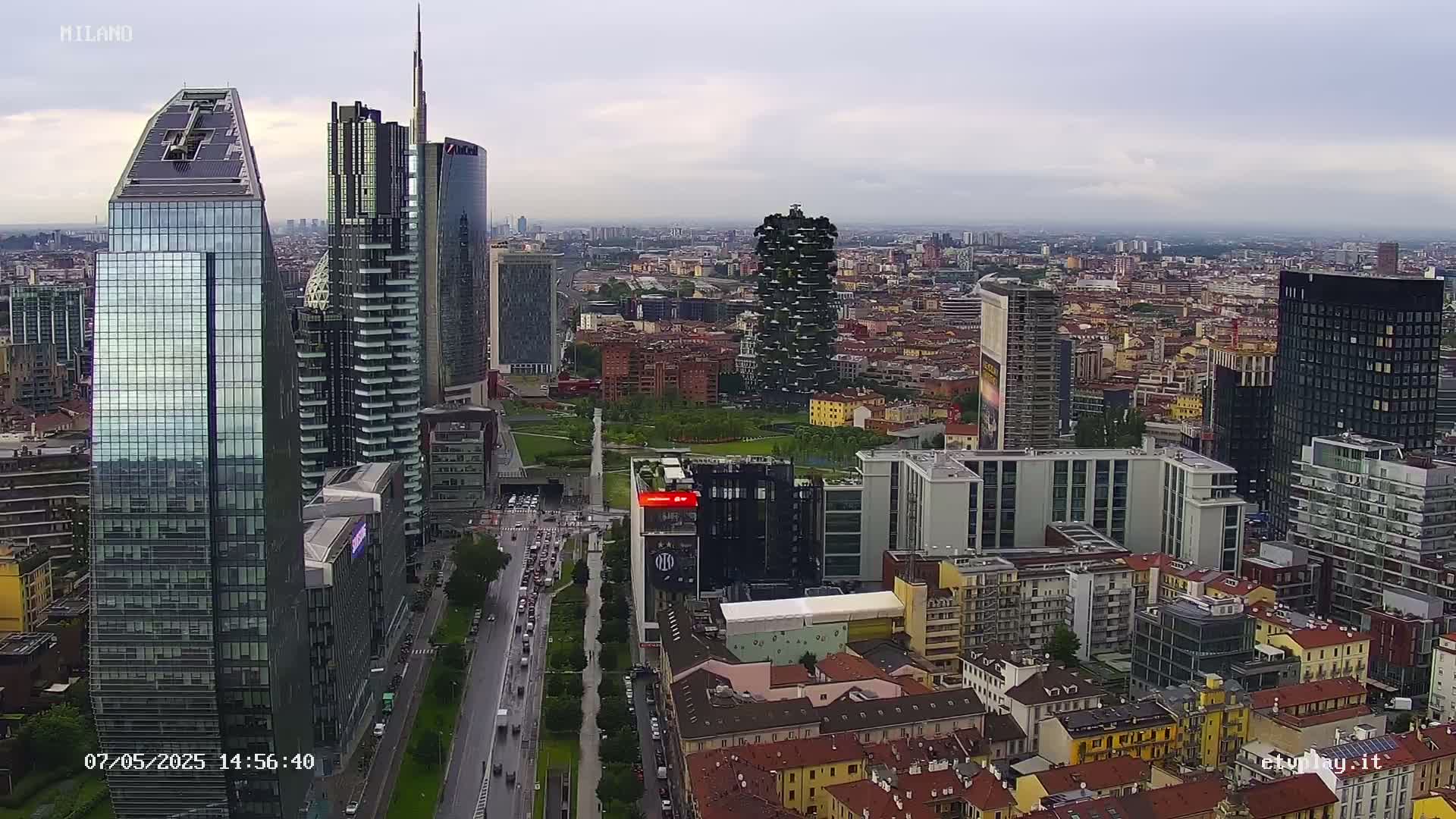 An aerial view of a city's skyline on an overcast day, showing numerous skyscrapers and surrounding buildings, with a highway visible in the foreground.
