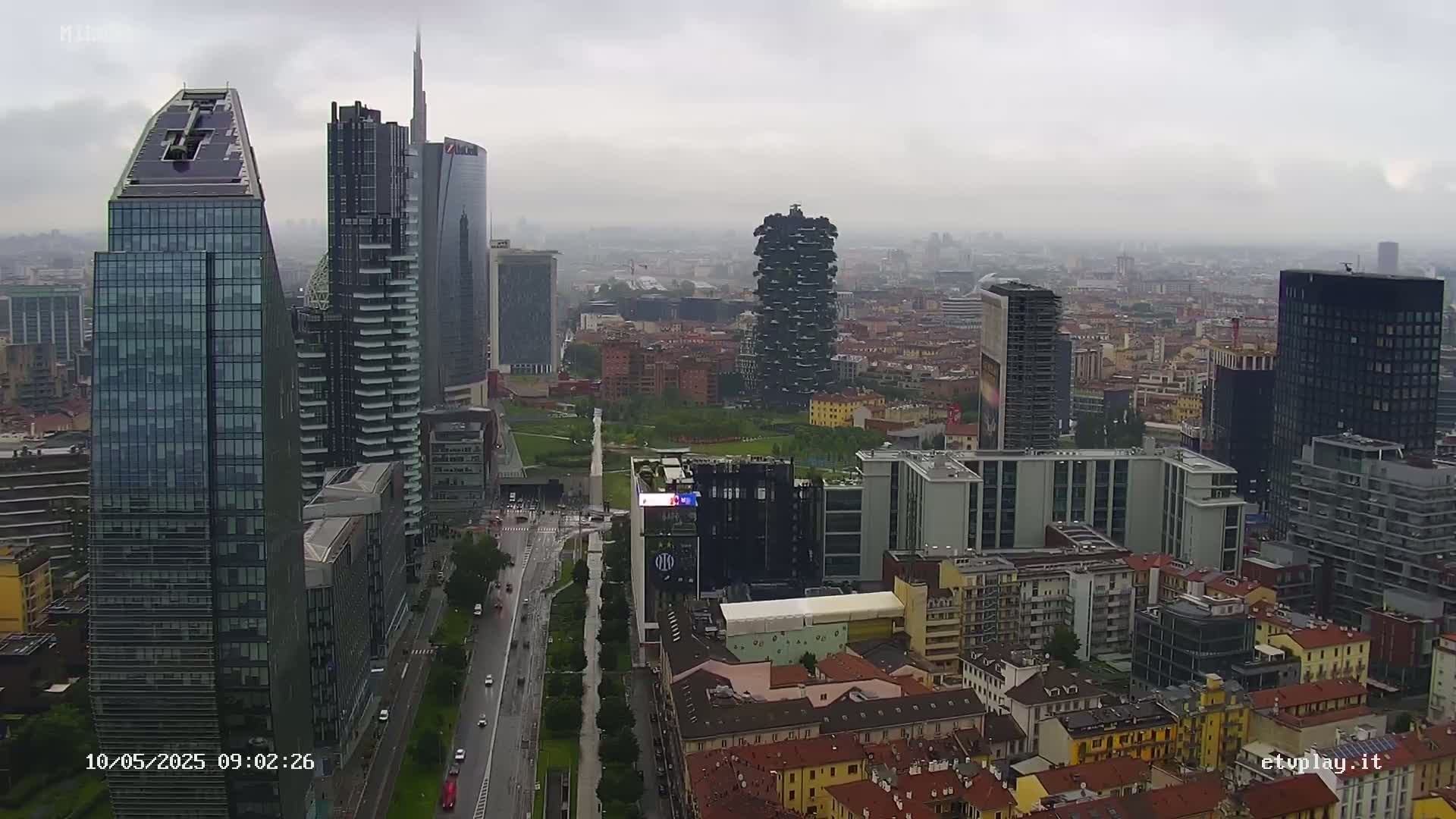 A rainy day aerial view of a city skyline showing numerous skyscrapers and surrounding buildings.