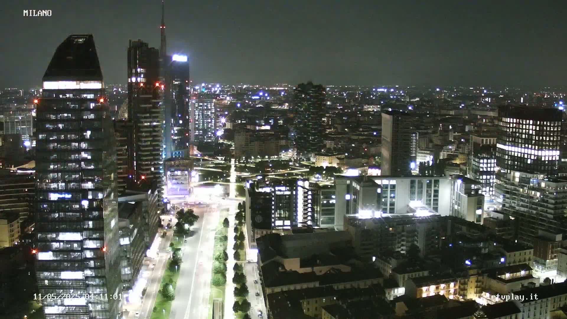 A nighttime aerial view of a city, showing numerous illuminated buildings and streets.