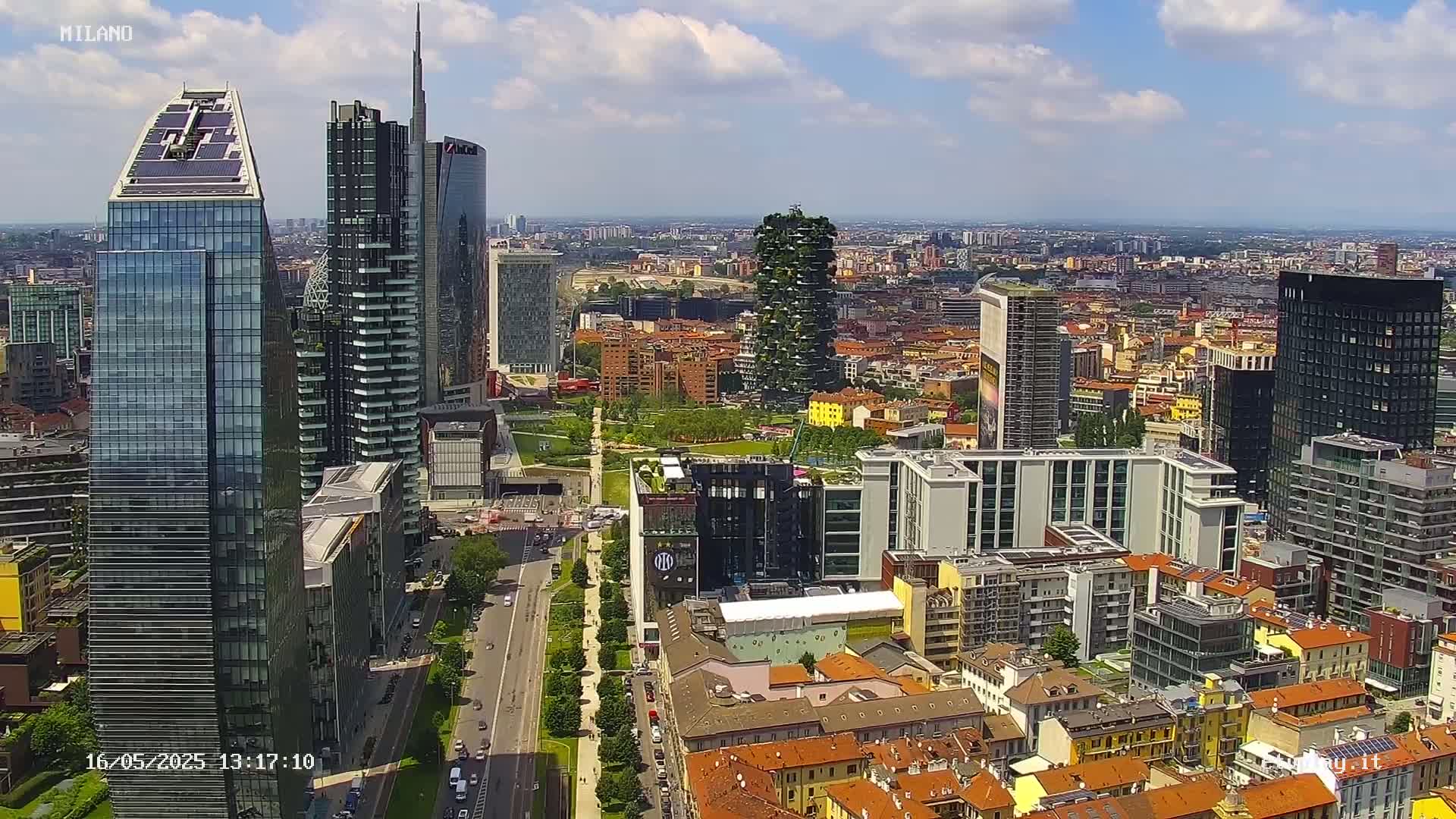An aerial view of a city with numerous skyscrapers and a mix of modern and traditional architecture under a partly cloudy sky.