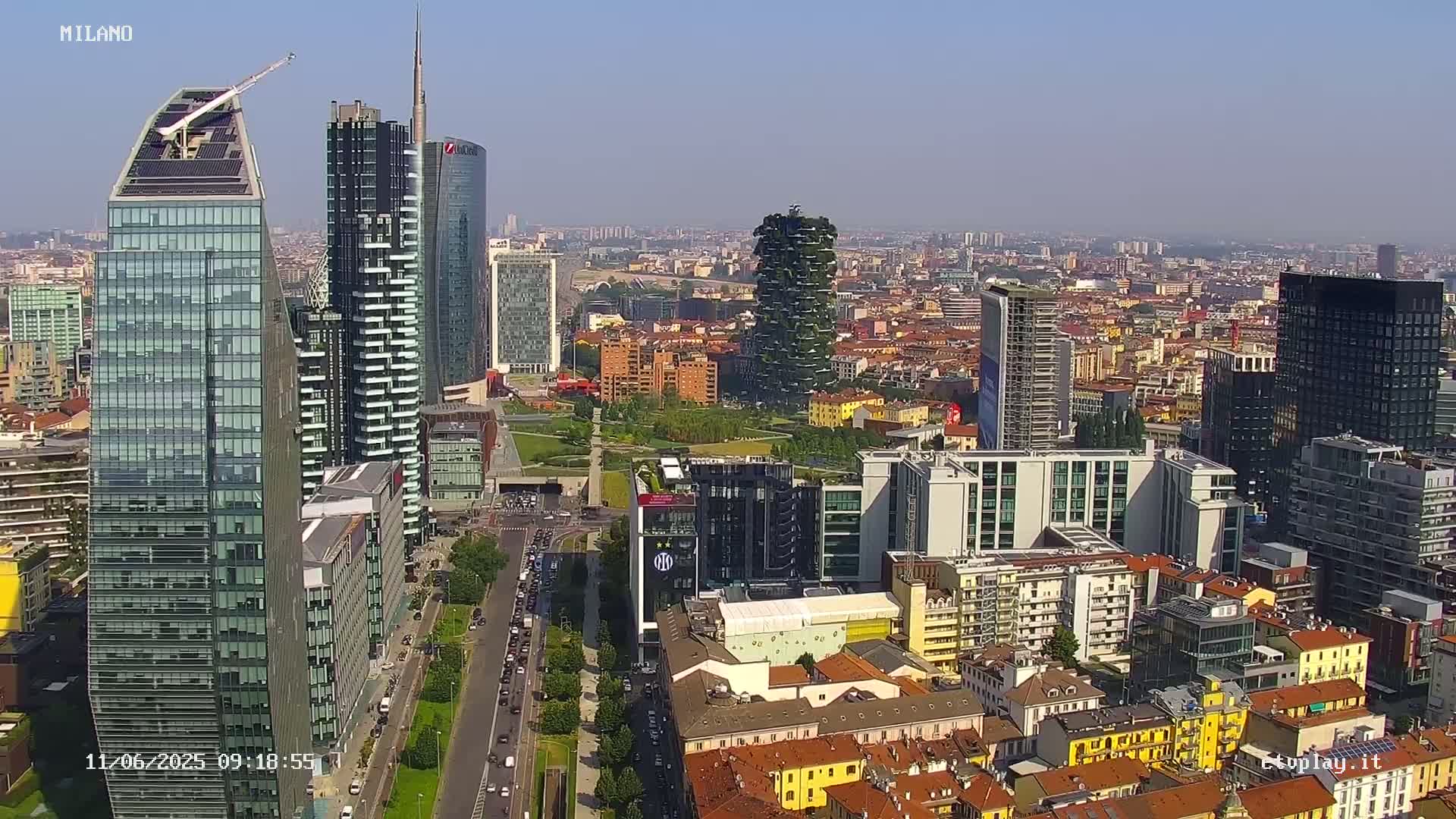 An aerial view of a city skyline on a clear, sunny day, showing many skyscrapers and surrounding buildings.