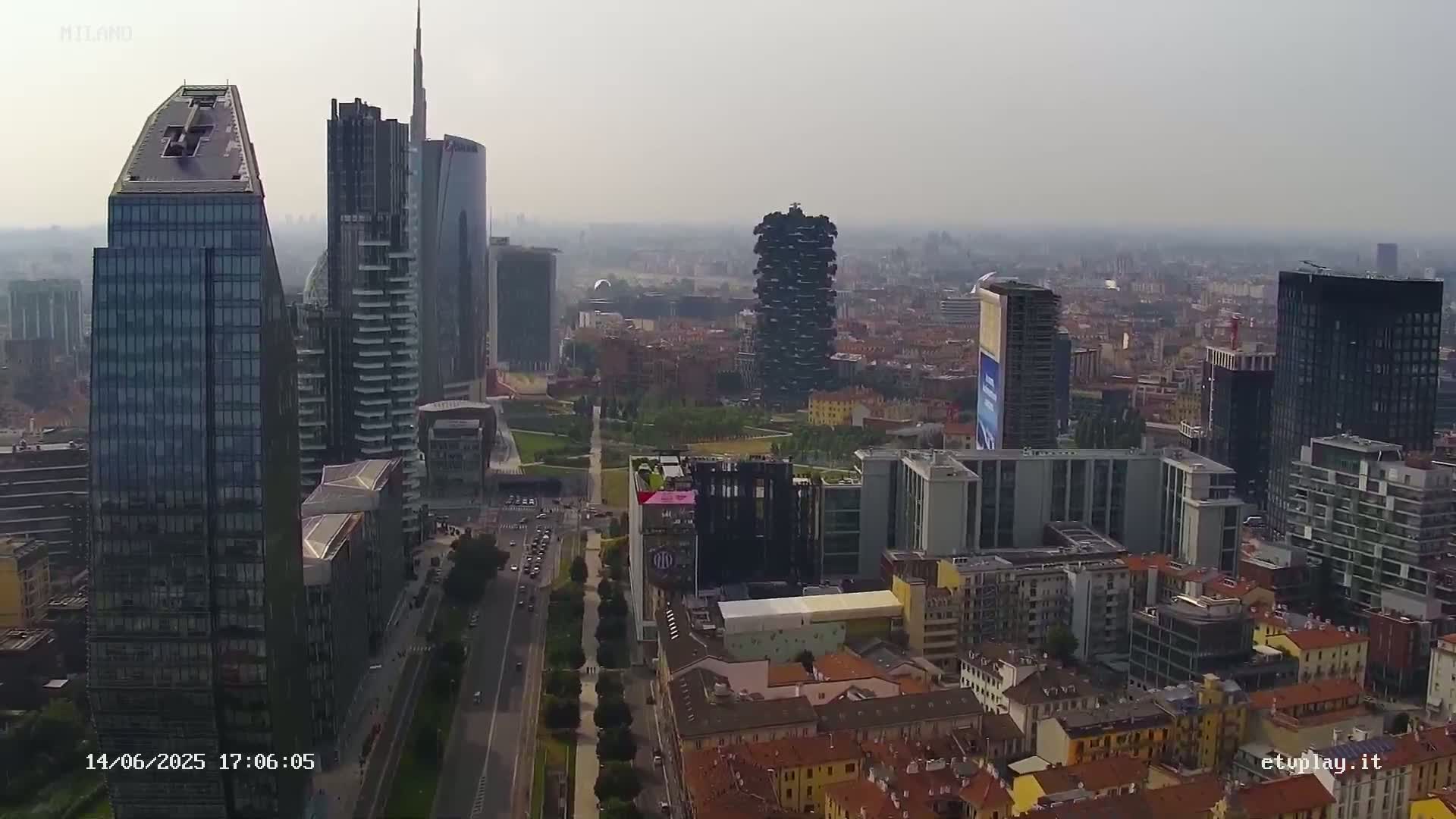 An aerial view shows a city skyline of numerous skyscrapers and high-rise buildings under hazy conditions.