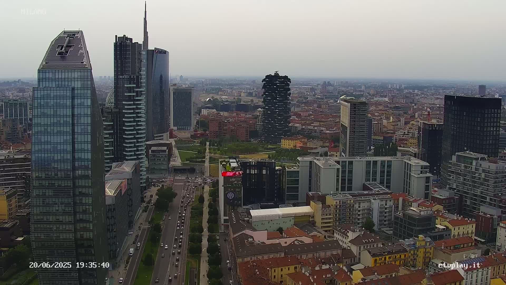 An aerial view shows a cityscape of numerous skyscrapers and high-rise buildings on a hazy day.