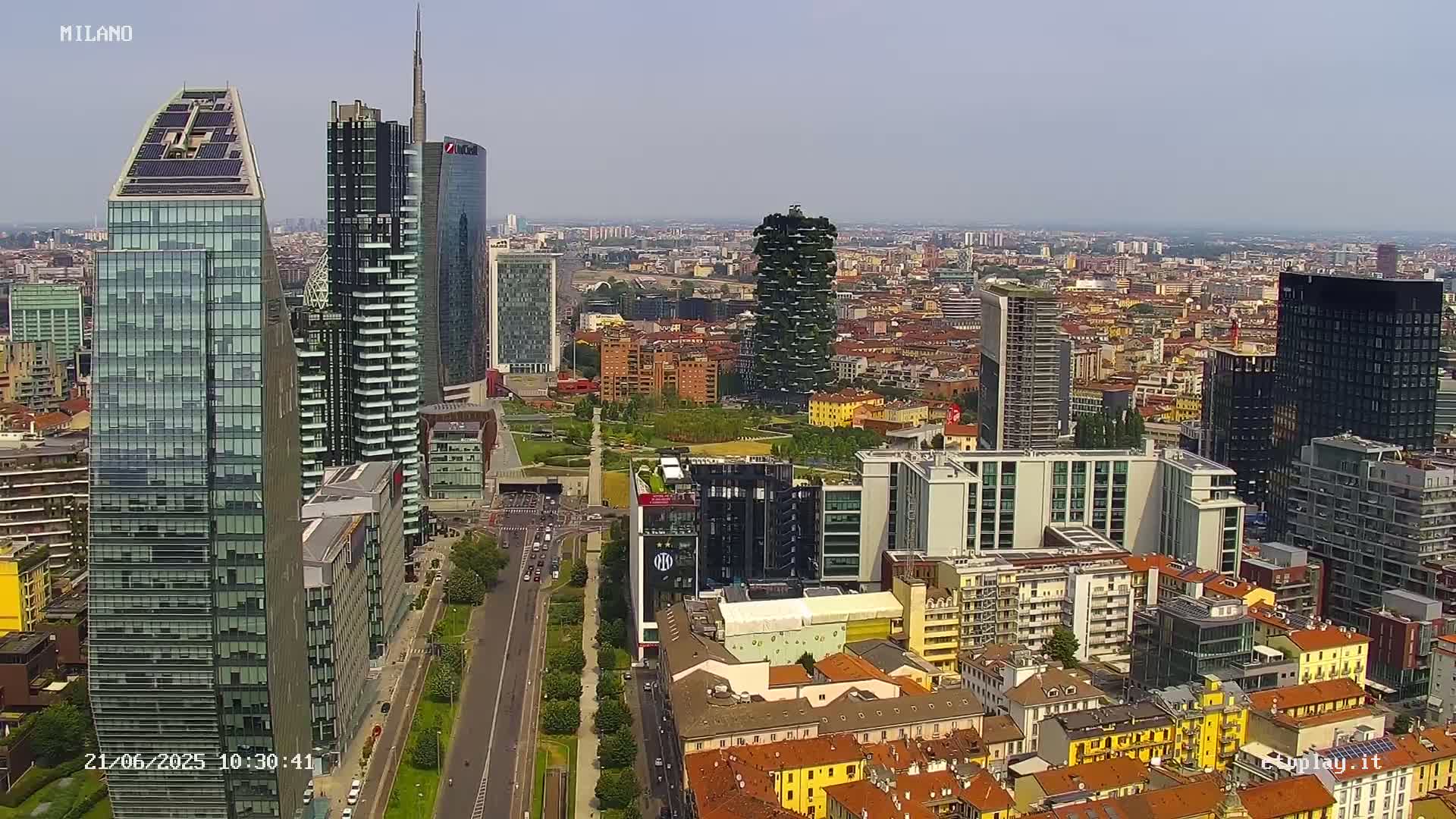 A high-angle, long shot of a city with many skyscrapers under a clear sky.