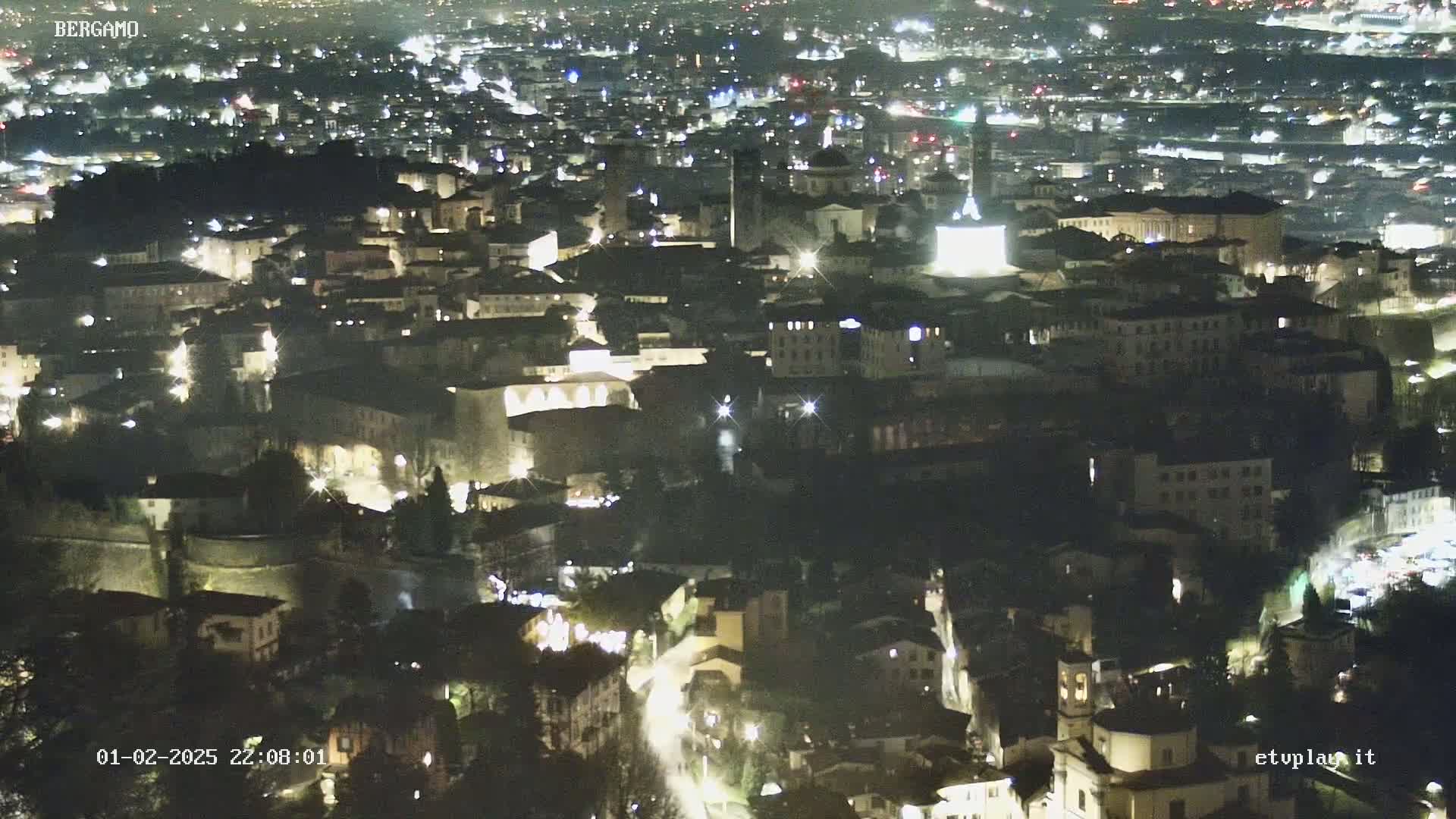 A nighttime, high-angle view of a city illuminated by streetlights.