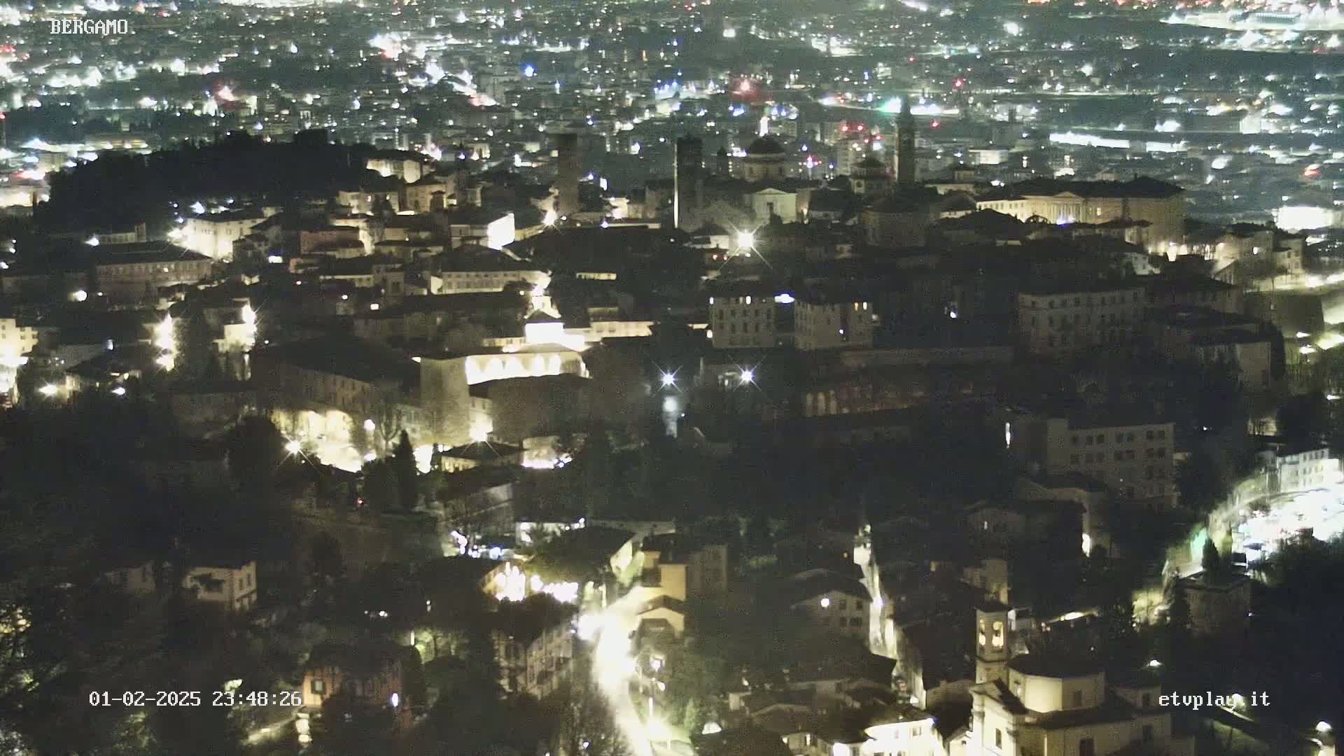 A nighttime aerial view of a city with illuminated buildings and streets.