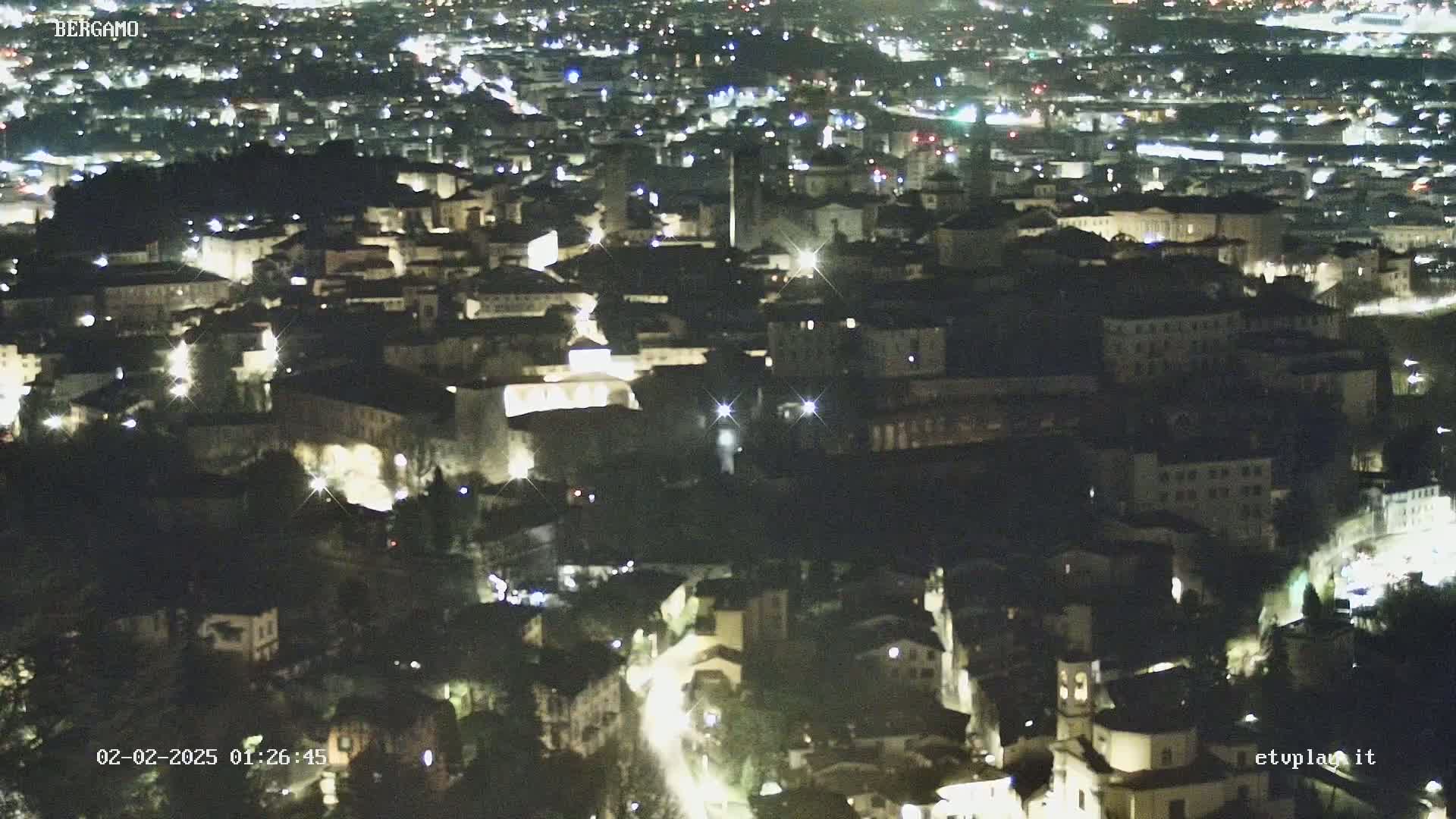 A nighttime, aerial view of a city with many buildings lit up.