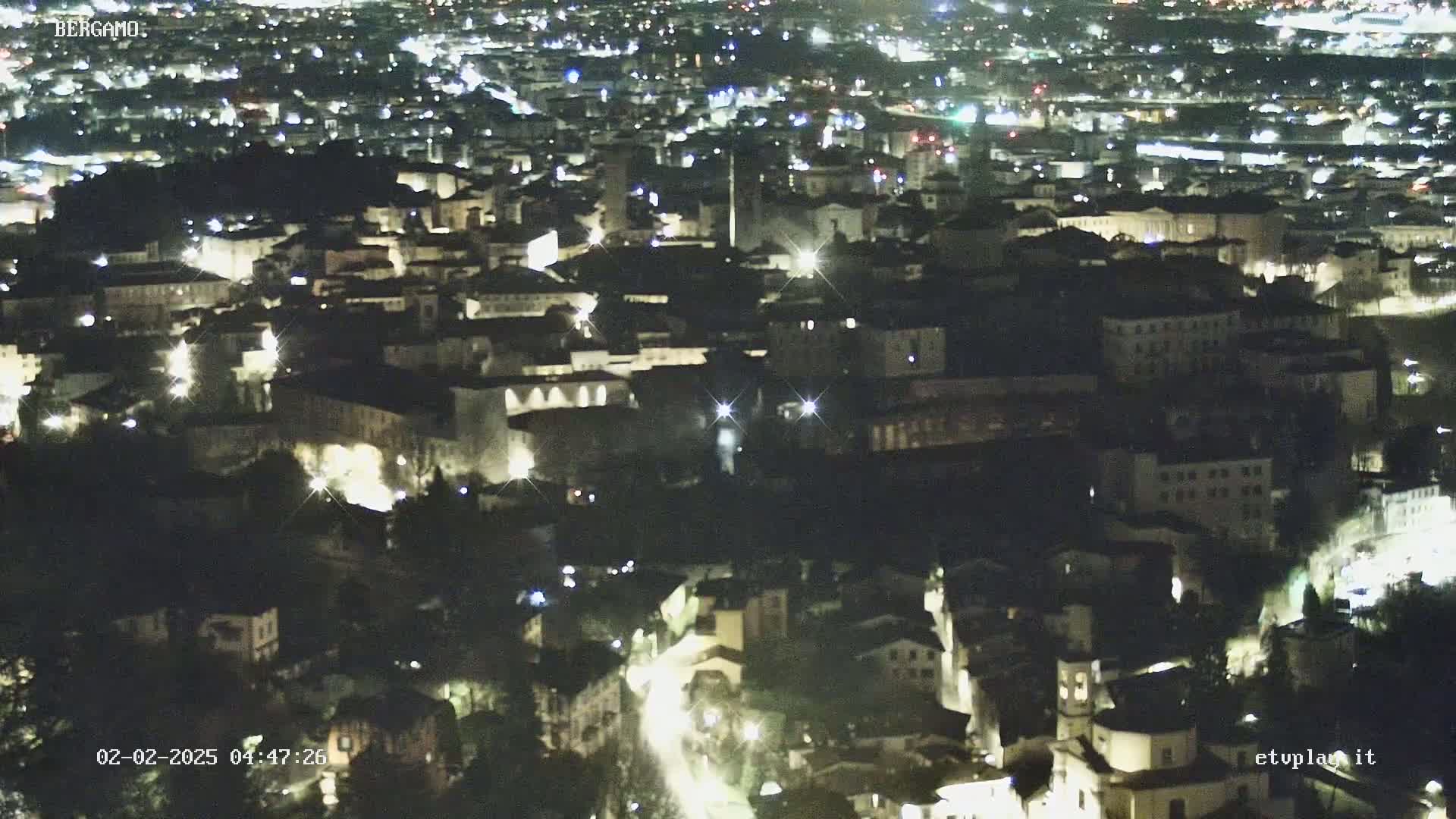 A nighttime aerial view of a city, with many lights illuminating buildings and streets.