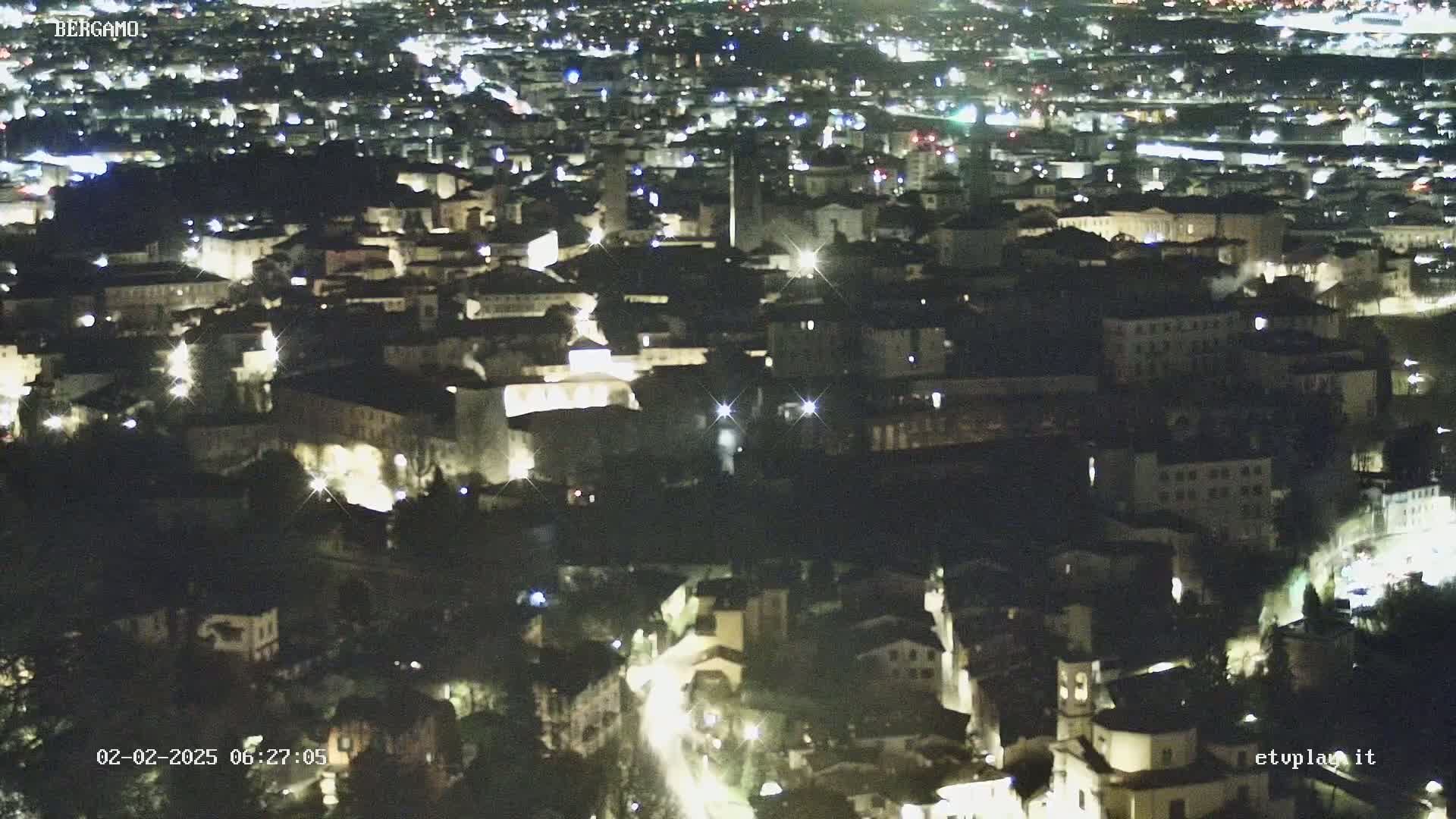 A nighttime aerial view of a city illuminated by streetlights and building lights.
