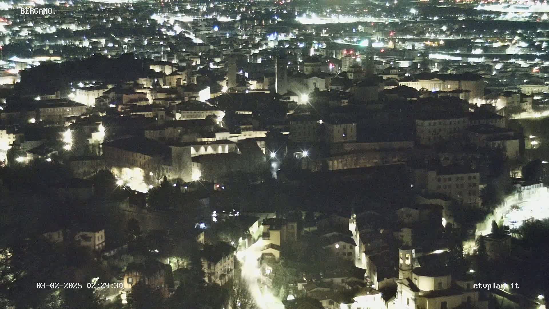 A nighttime aerial view of a city with buildings illuminated by lights.