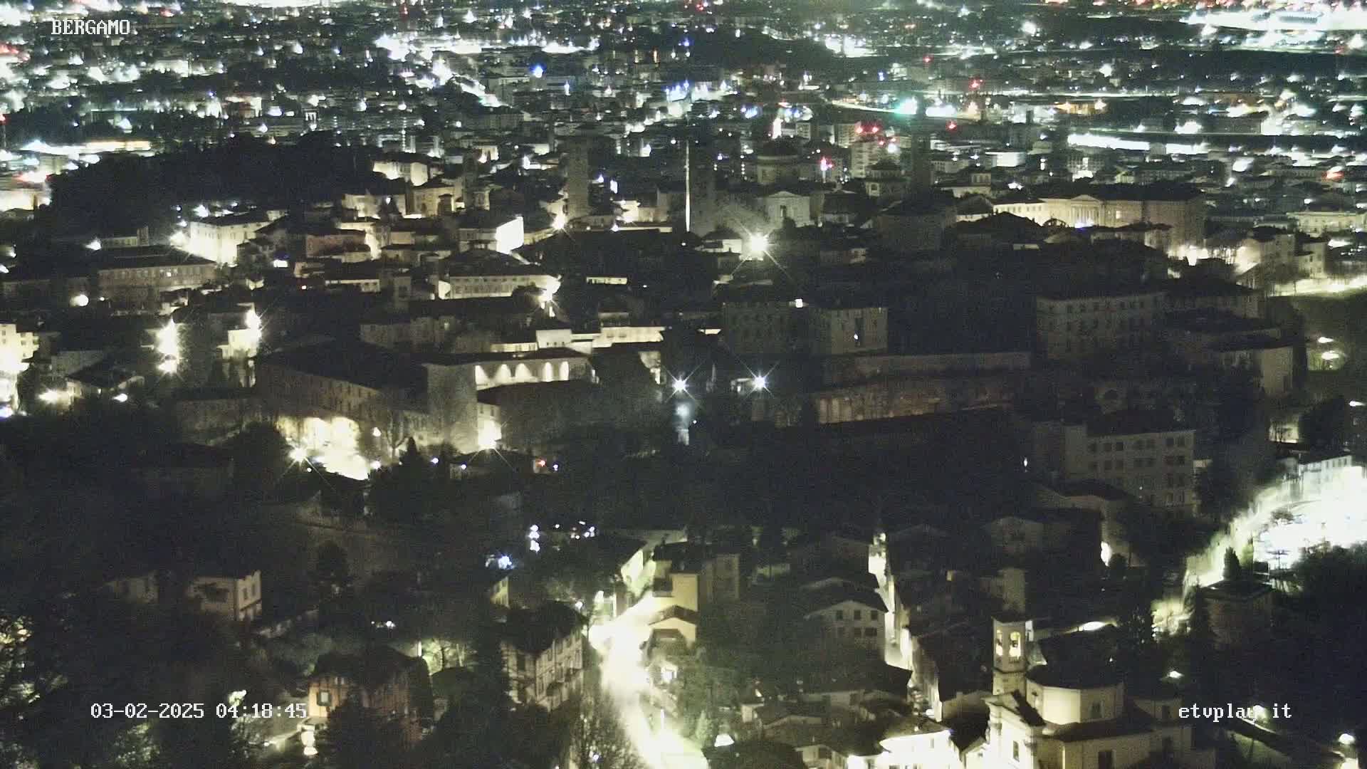 A nighttime aerial view of a city with many buildings lit up.