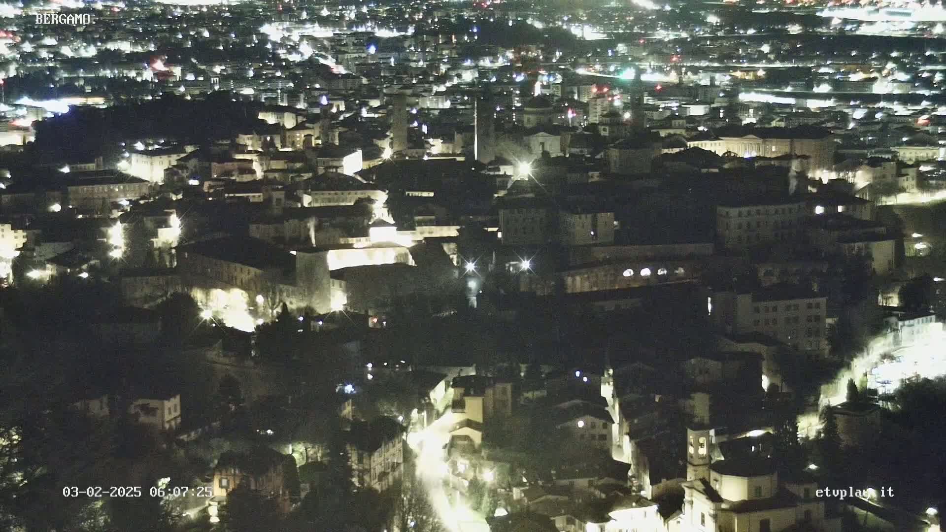 A nighttime, high-angle view of a city with illuminated buildings and streets.