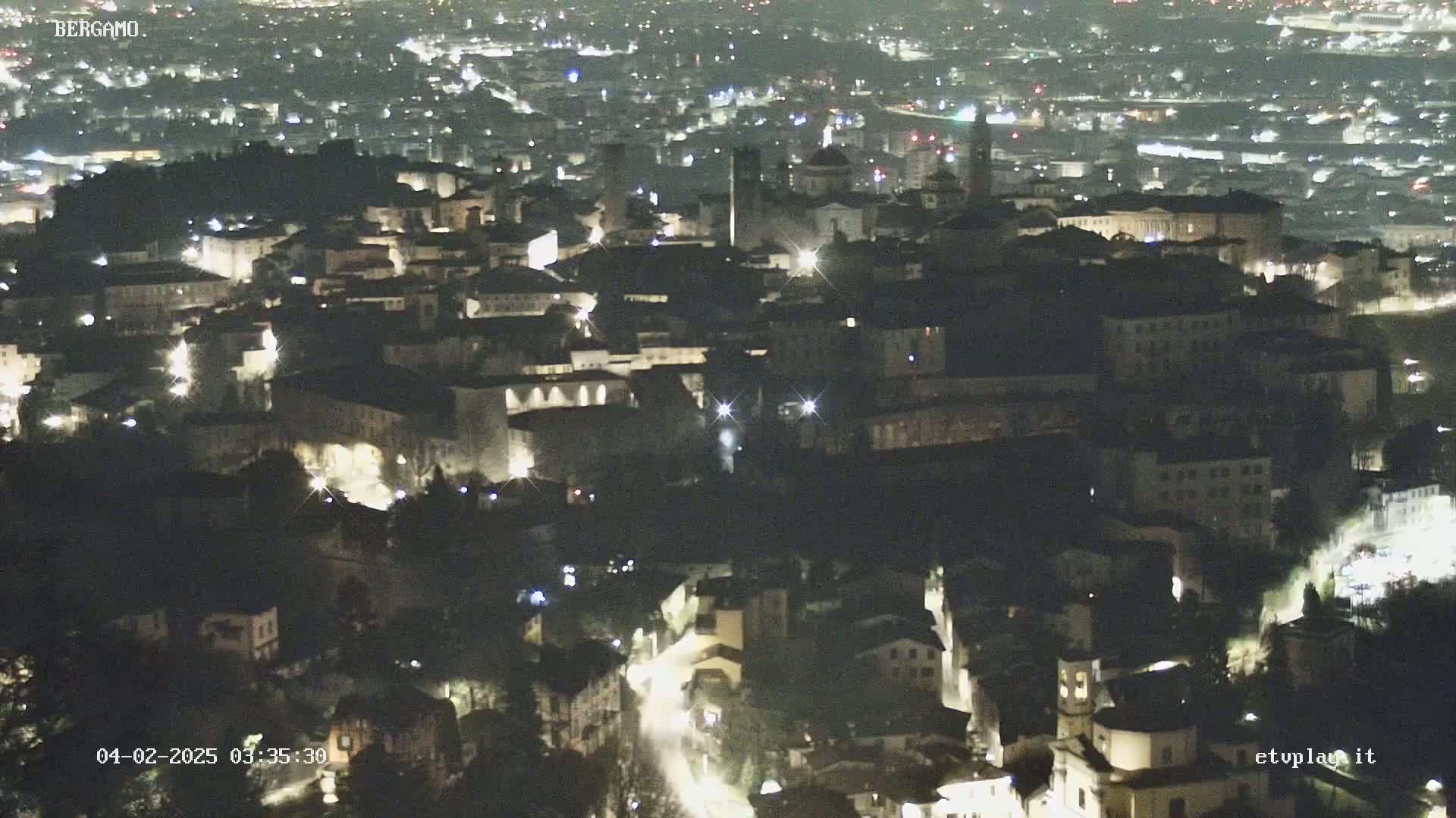 A nighttime aerial view of a city, illuminated by streetlights and building lights.